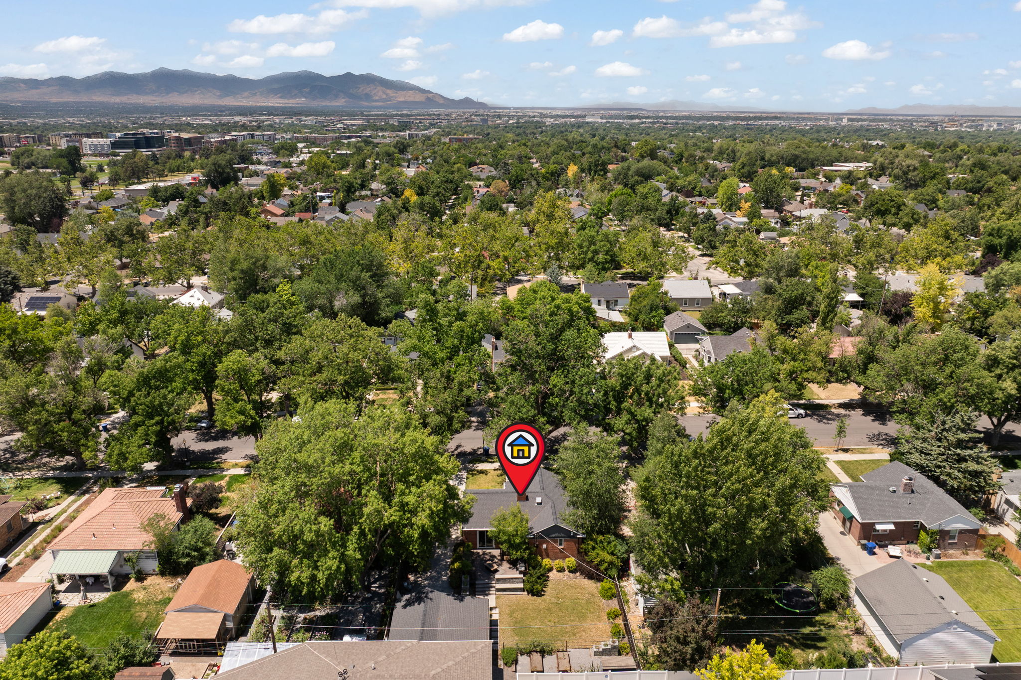 Residential property situated within a tree-lined neighborhood, featuring a mountain range backdrop