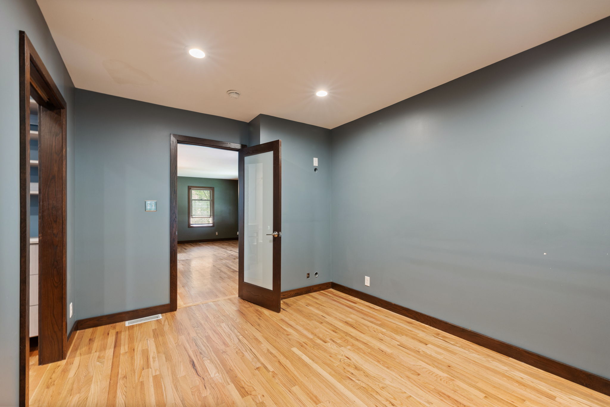 Hardwood flooring throughout featuring dark wood trim and doors, recessed lighting, and a frosted glass panel door