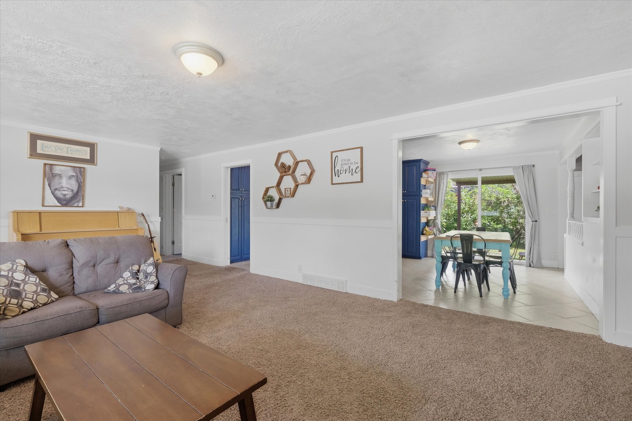 Spacious living area featuring neutral carpeting and white wainscoting