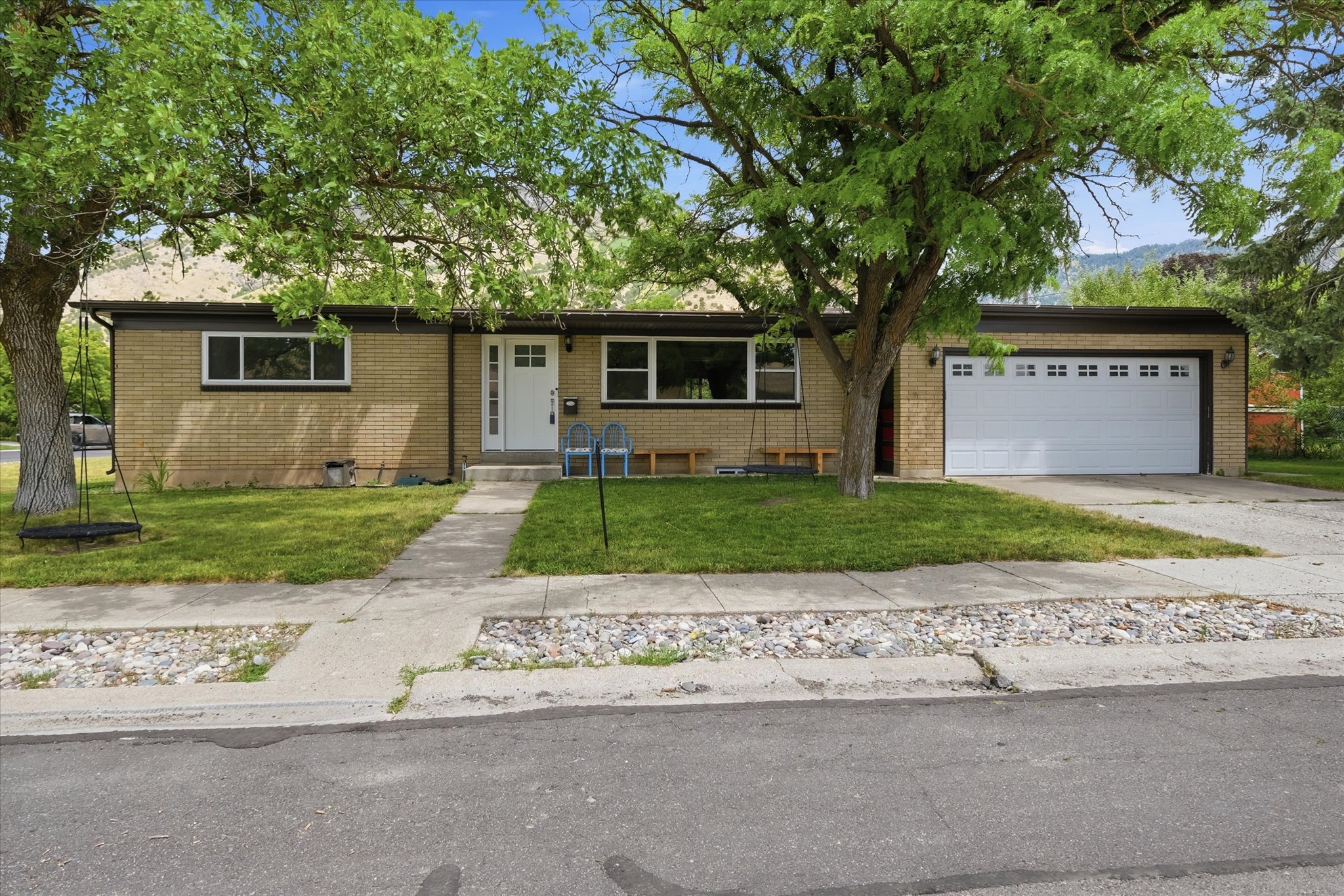 Brick exterior featuring a two-car garage with paneling and window inserts