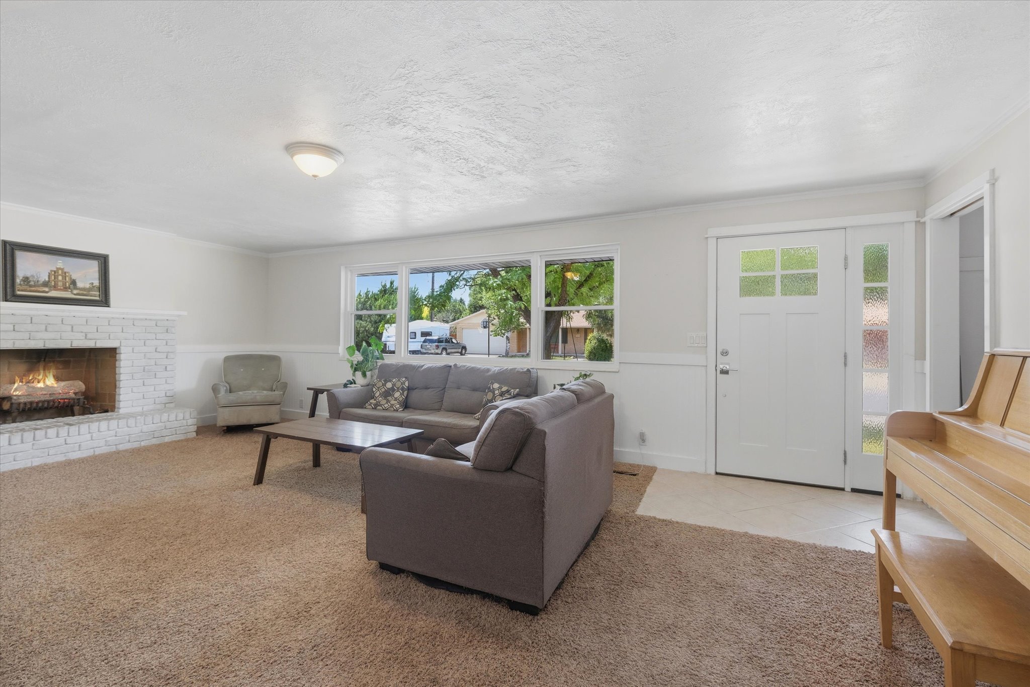 Bright living area featuring a white brick fireplace, expansive window, and neutral wall tones