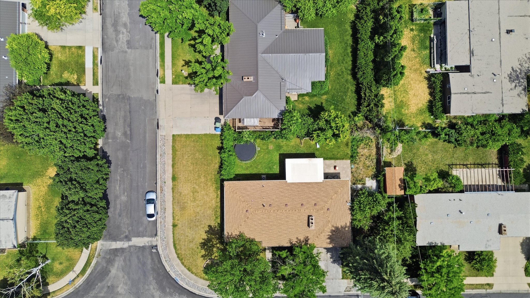 Aerial perspective showcasing a residential property with a brown shingle roof and surrounding green spaces