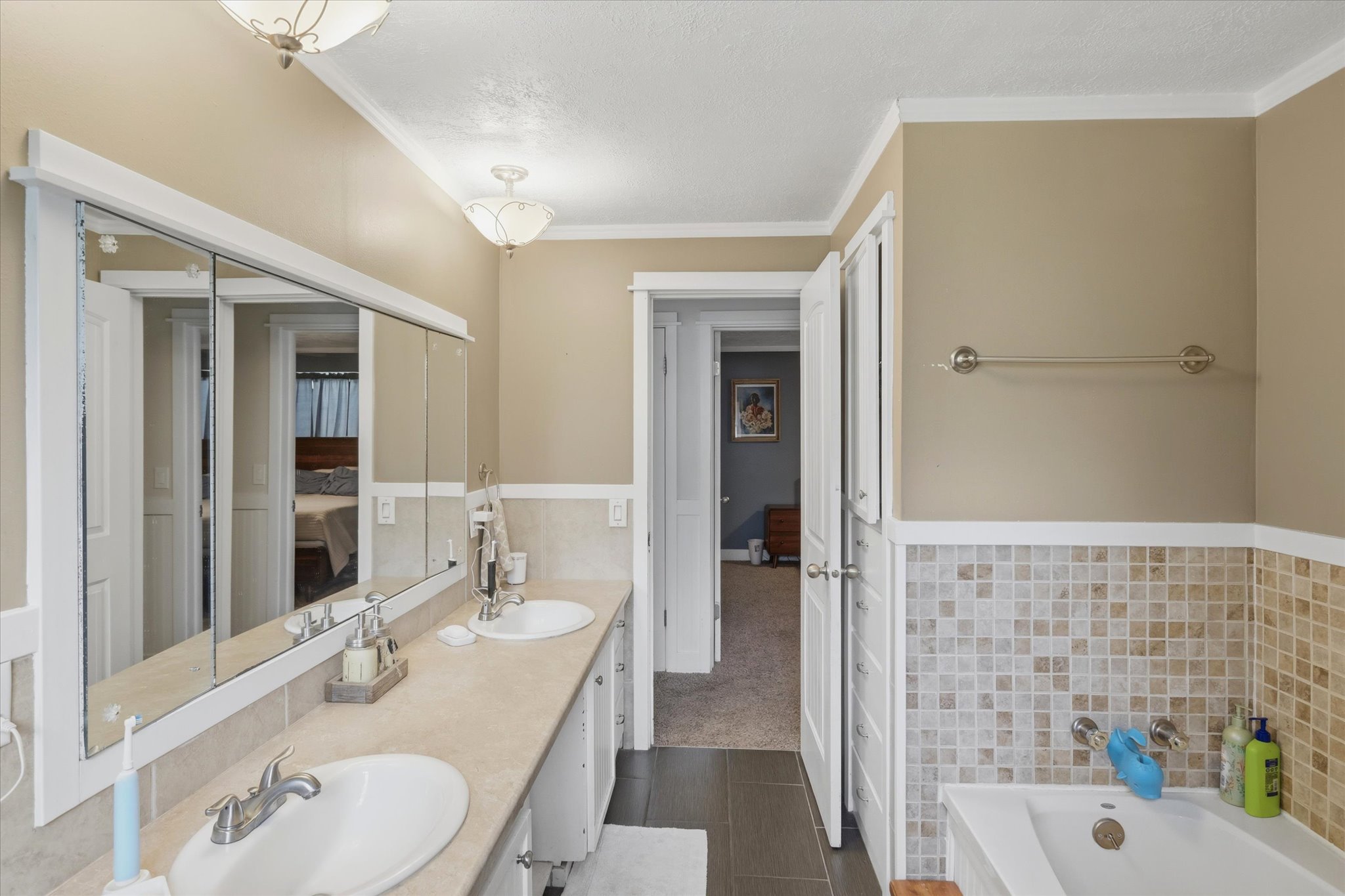 Dual vanity with integrated sinks and extensive counter space, complemented by a large mirrored medicine cabinet