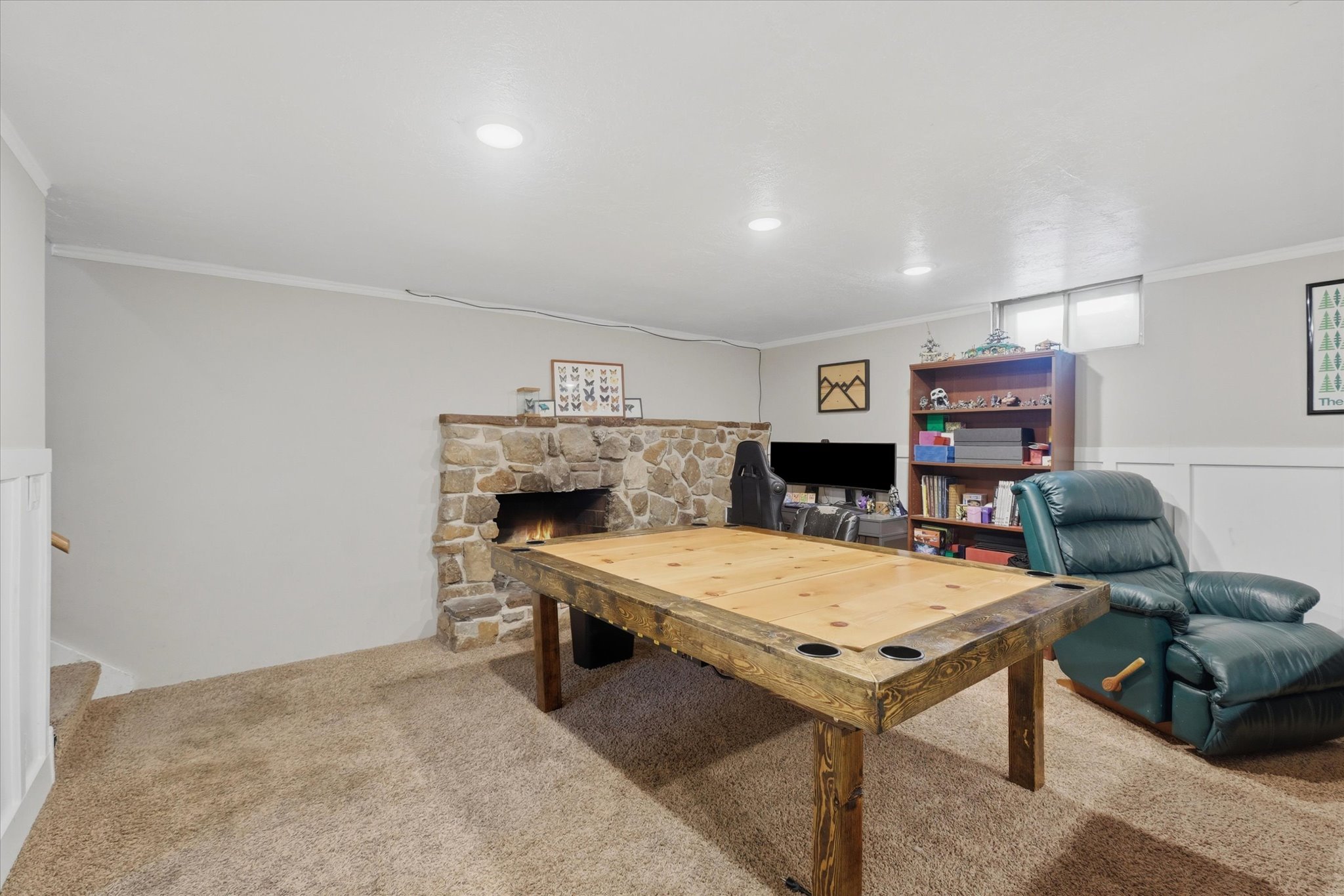Recreation room featuring a stone fireplace, recessed lighting, and a window for natural light