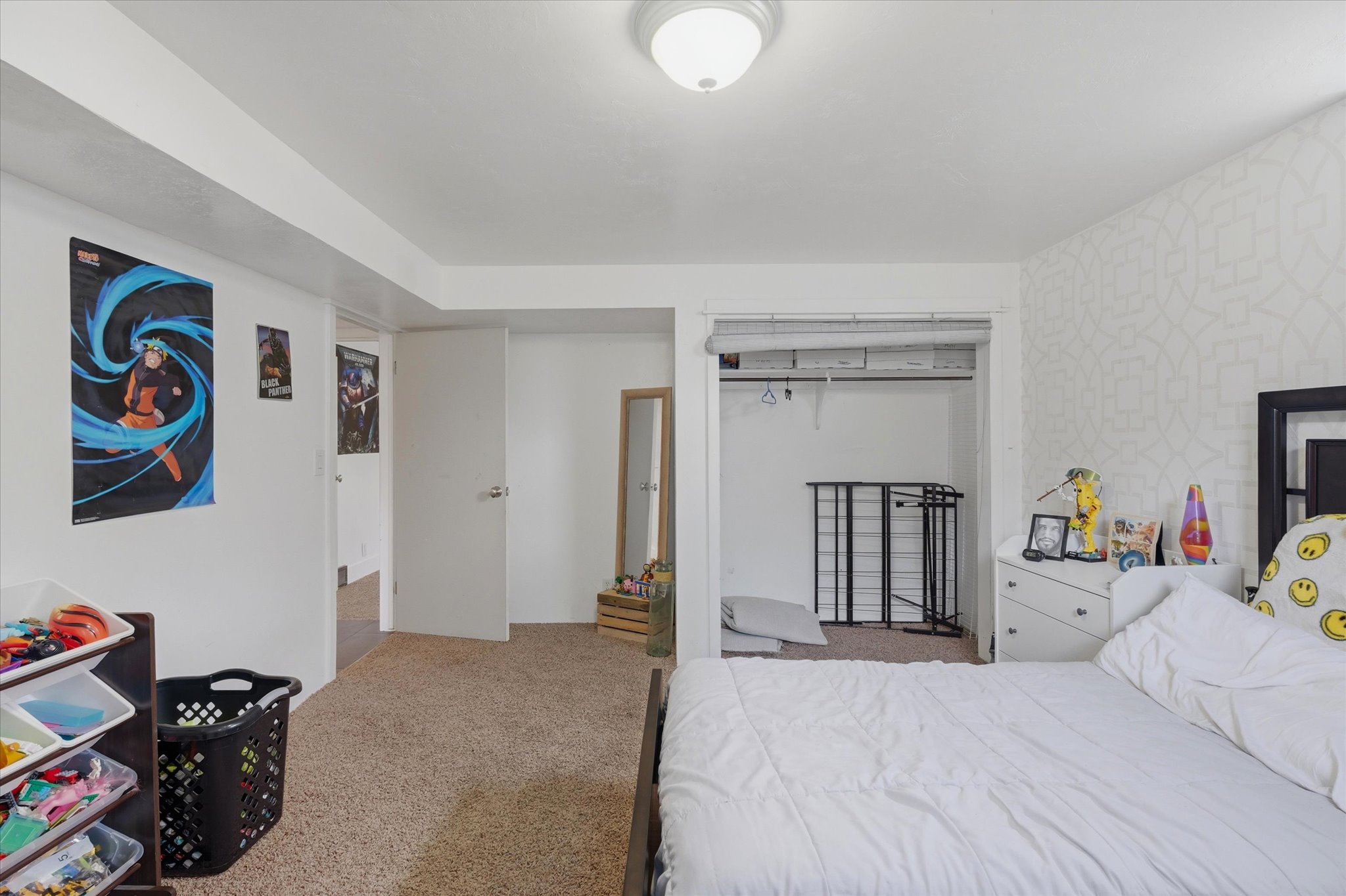 Carpeted room with white walls, a flush-mount ceiling light, and a patterned accent wall