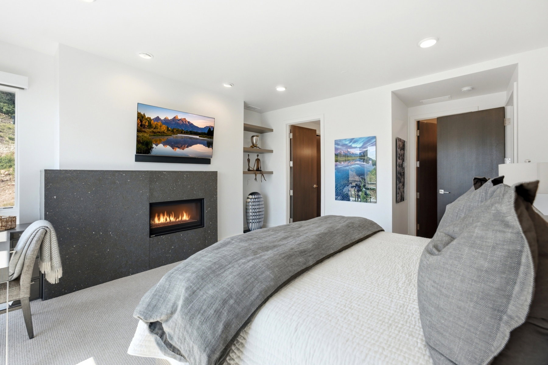 Bedroom featuring a modern fireplace with a dark stone surround, recessed lighting, and built-in shelving