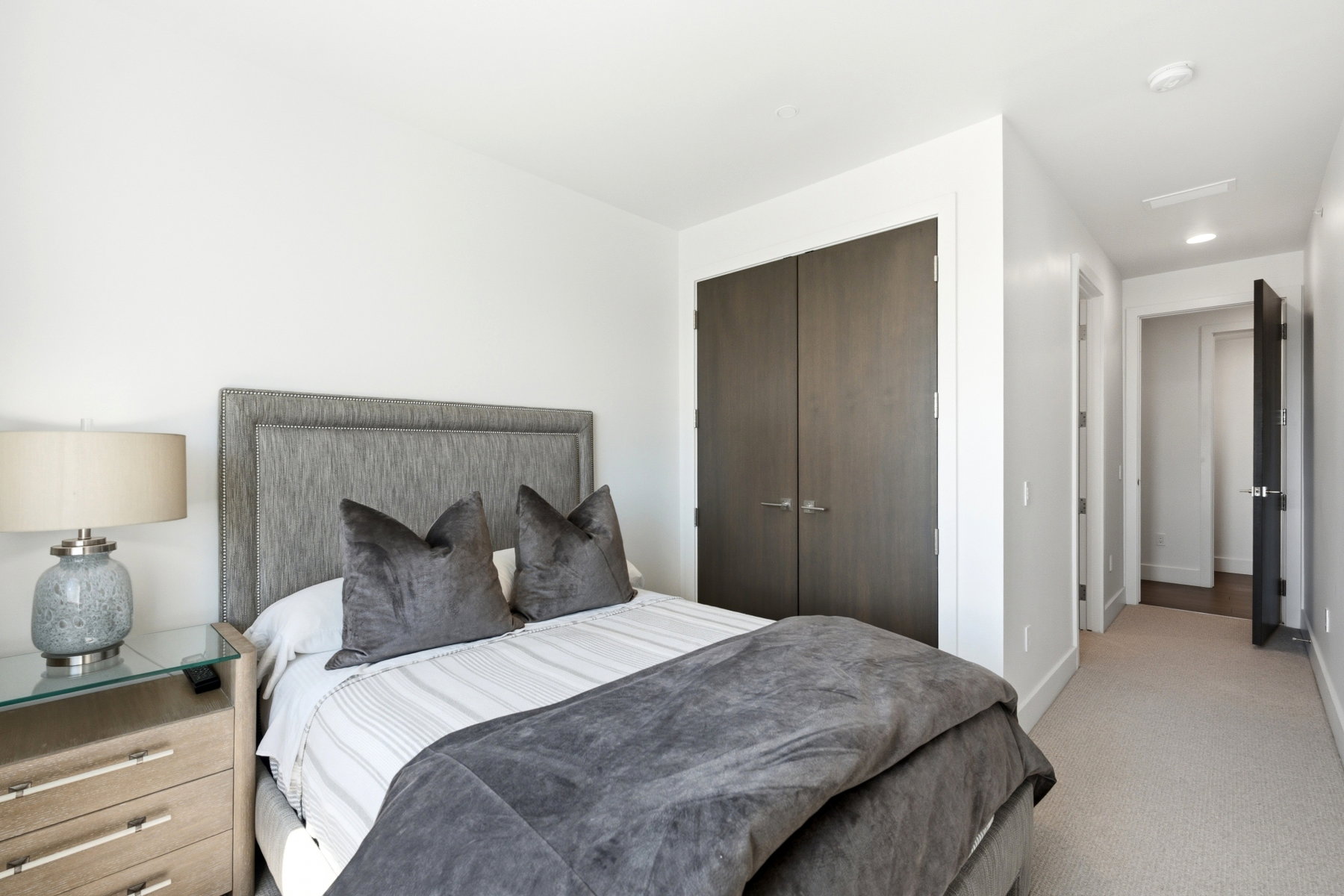 Bedroom featuring a neutral upholstered headboard, built-in closet with dark wood-finish doors, and plush carpet flooring