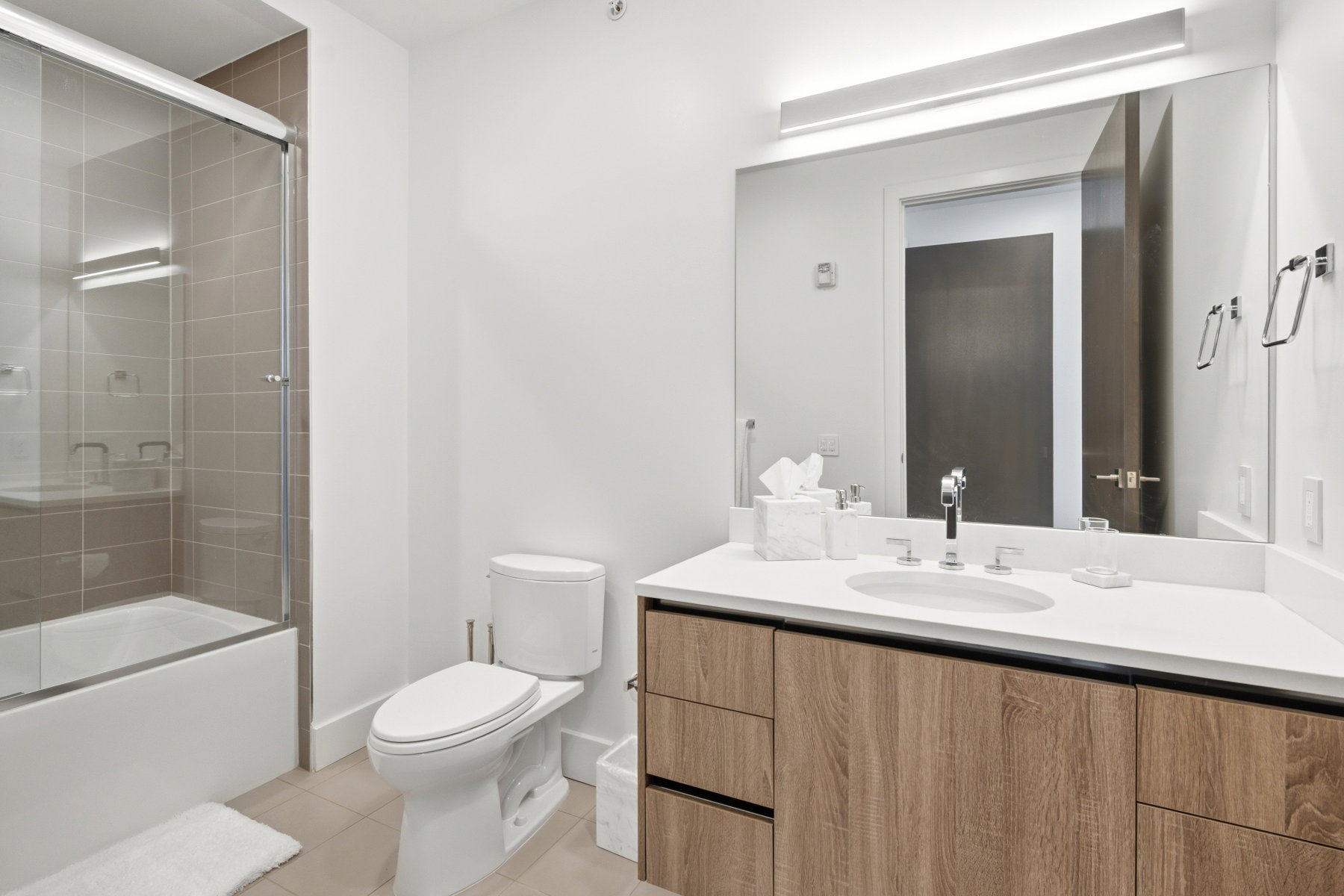 Full bathroom featuring a single vanity with wood-finish cabinetry, a white countertop, and an undermount sink