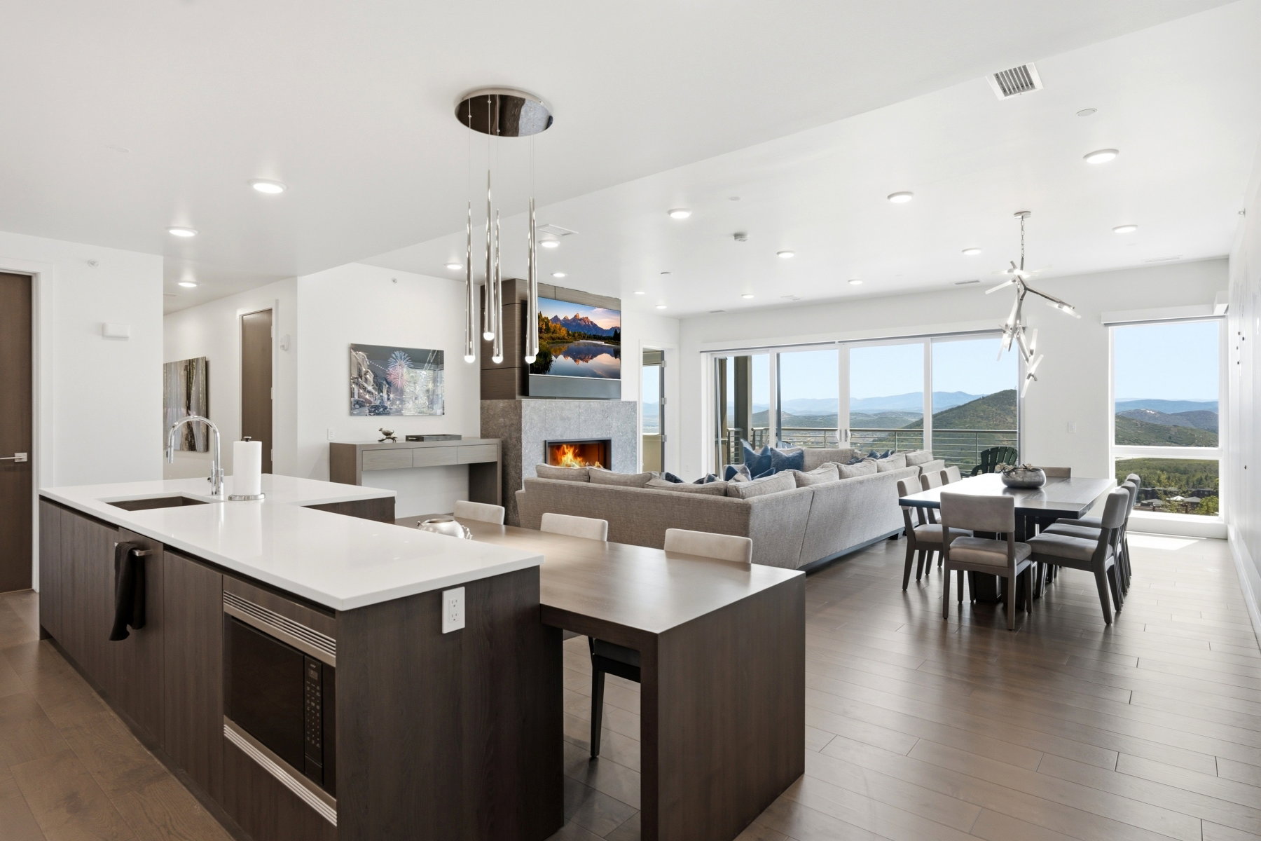 Open-concept living area featuring a kitchen island with white countertop, integrated microwave, and stainless steel sink