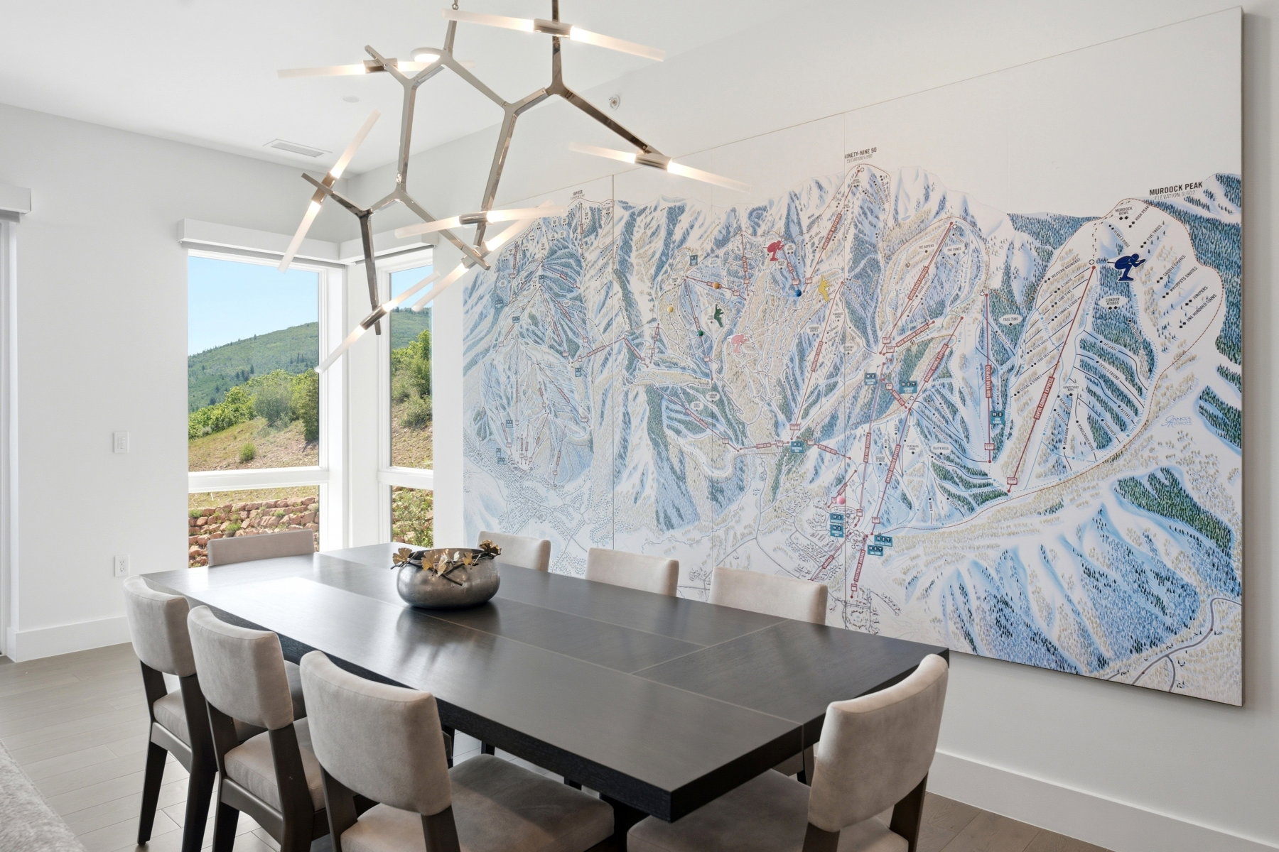 Spacious dining area featuring a modern linear chandelier, large picture windows, and light-toned flooring