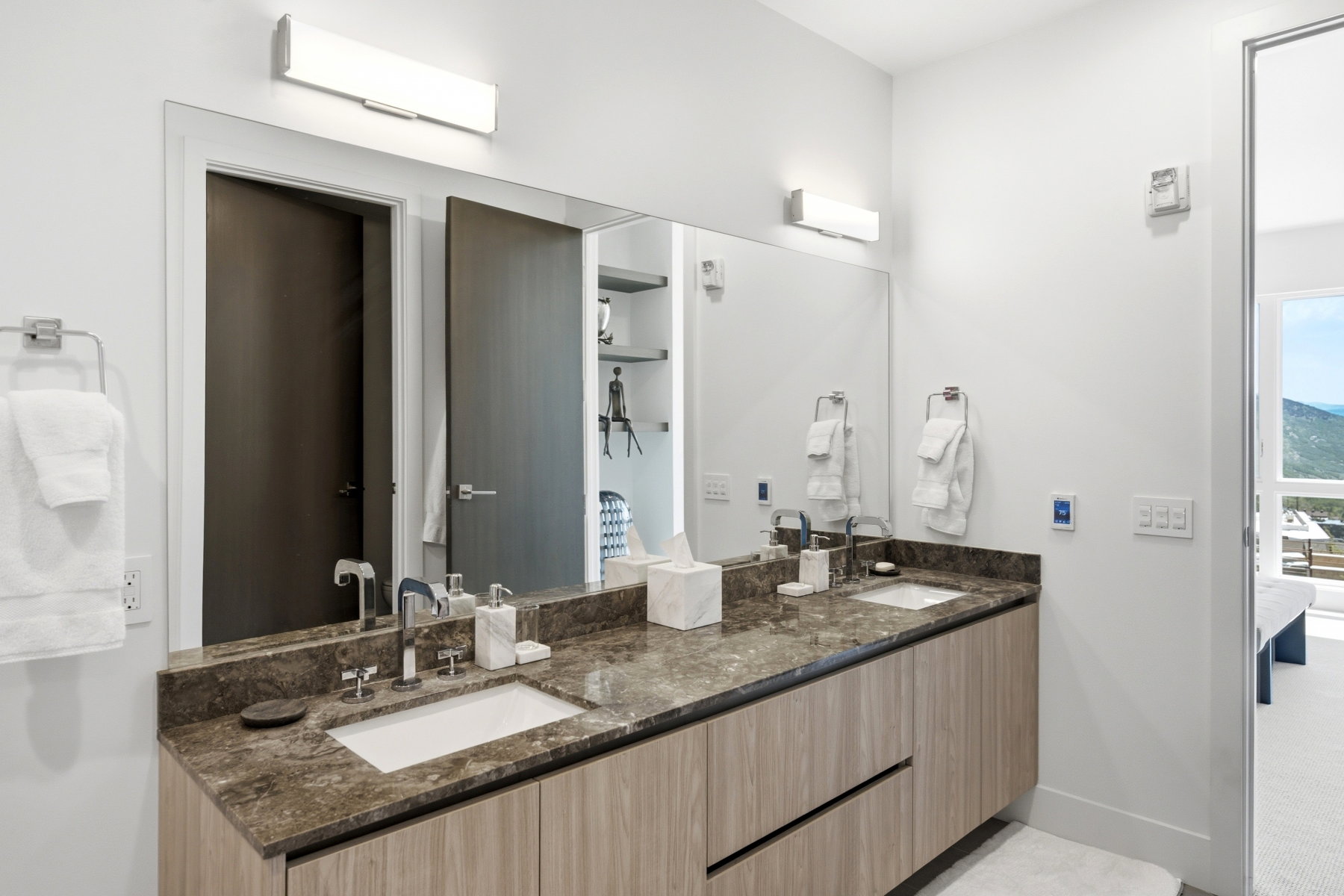 Dual vanity featuring a stone countertop with integrated sinks, wood-finish cabinetry, and chrome fixtures