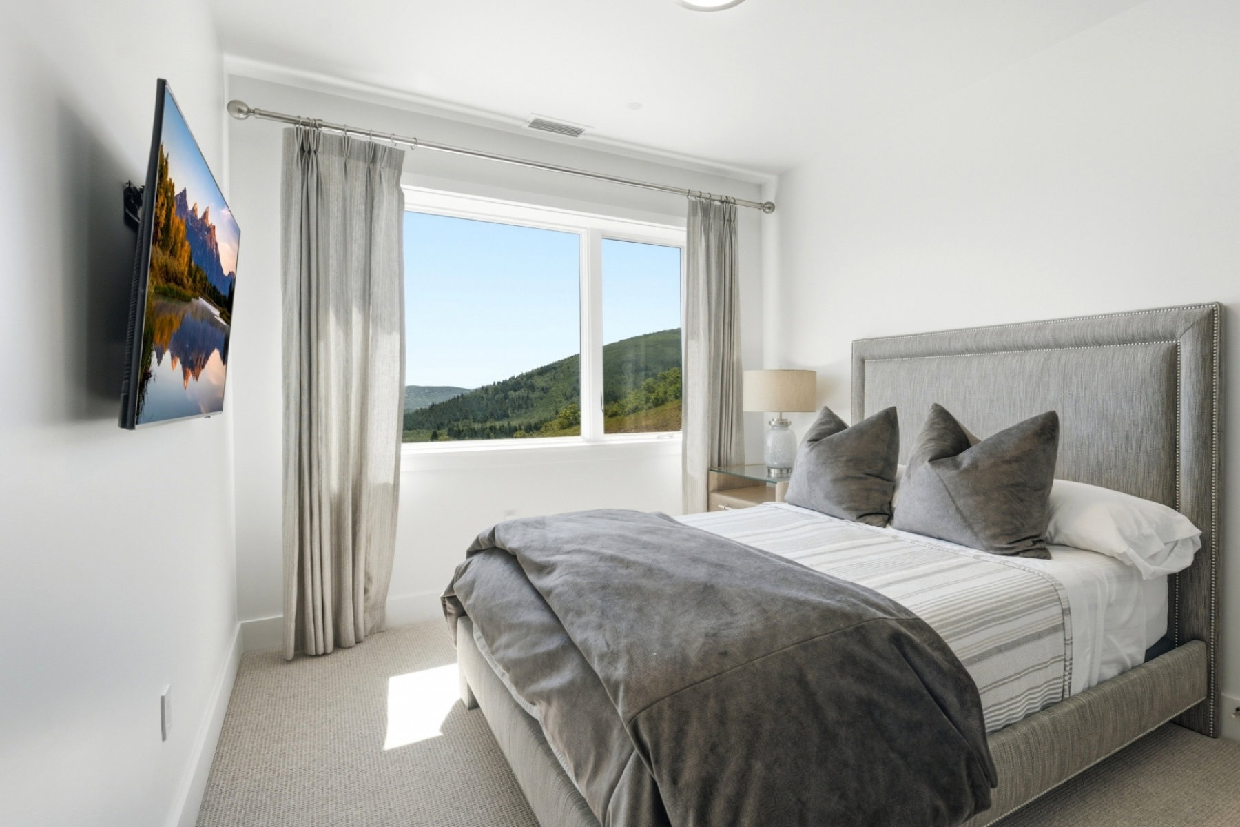 Bedroom featuring a large picture window, wall-to-wall carpeting, and a mountain landscape