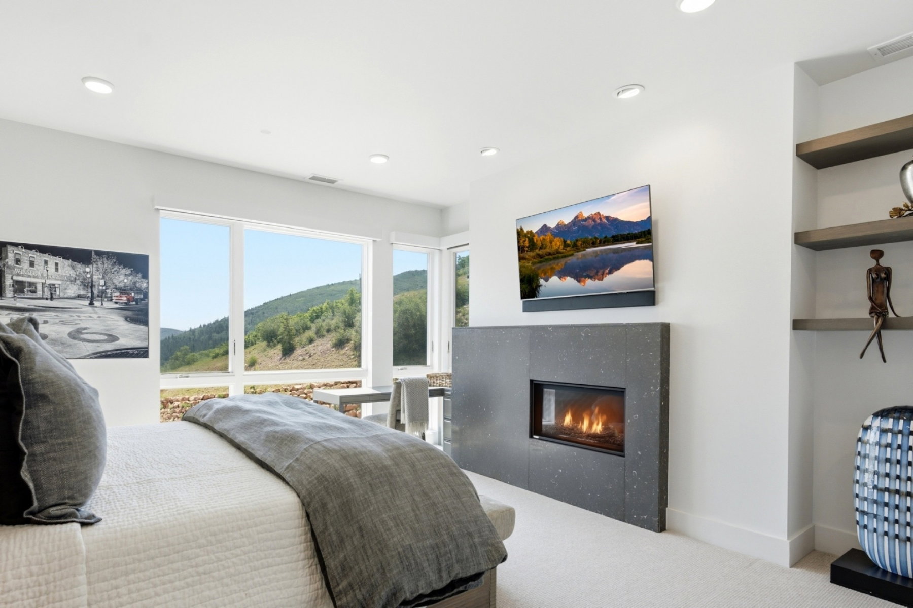 Spacious room with large windows, a stone-faced fireplace, recessed lighting, built-in shelving, and light-toned carpeting