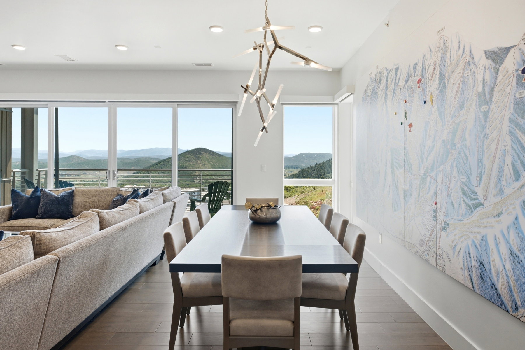 Spacious living area featuring expansive glass sliding doors, wood-finish flooring, recessed lighting, and a contemporary chandelier
