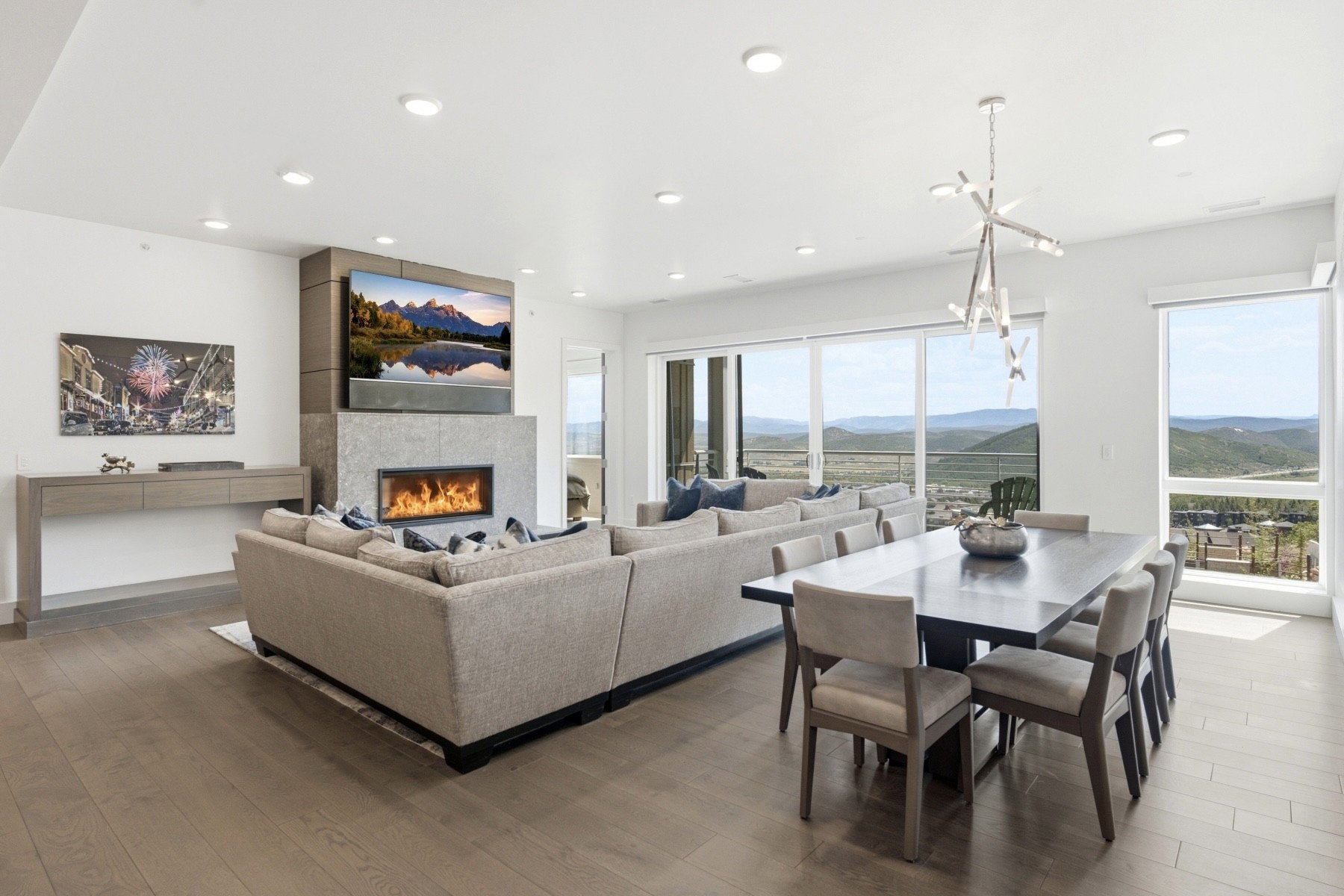 Open-concept living area featuring wood-finish flooring, a contemporary fireplace with a stone surround, recessed lighting, and expansive sliding glass doors