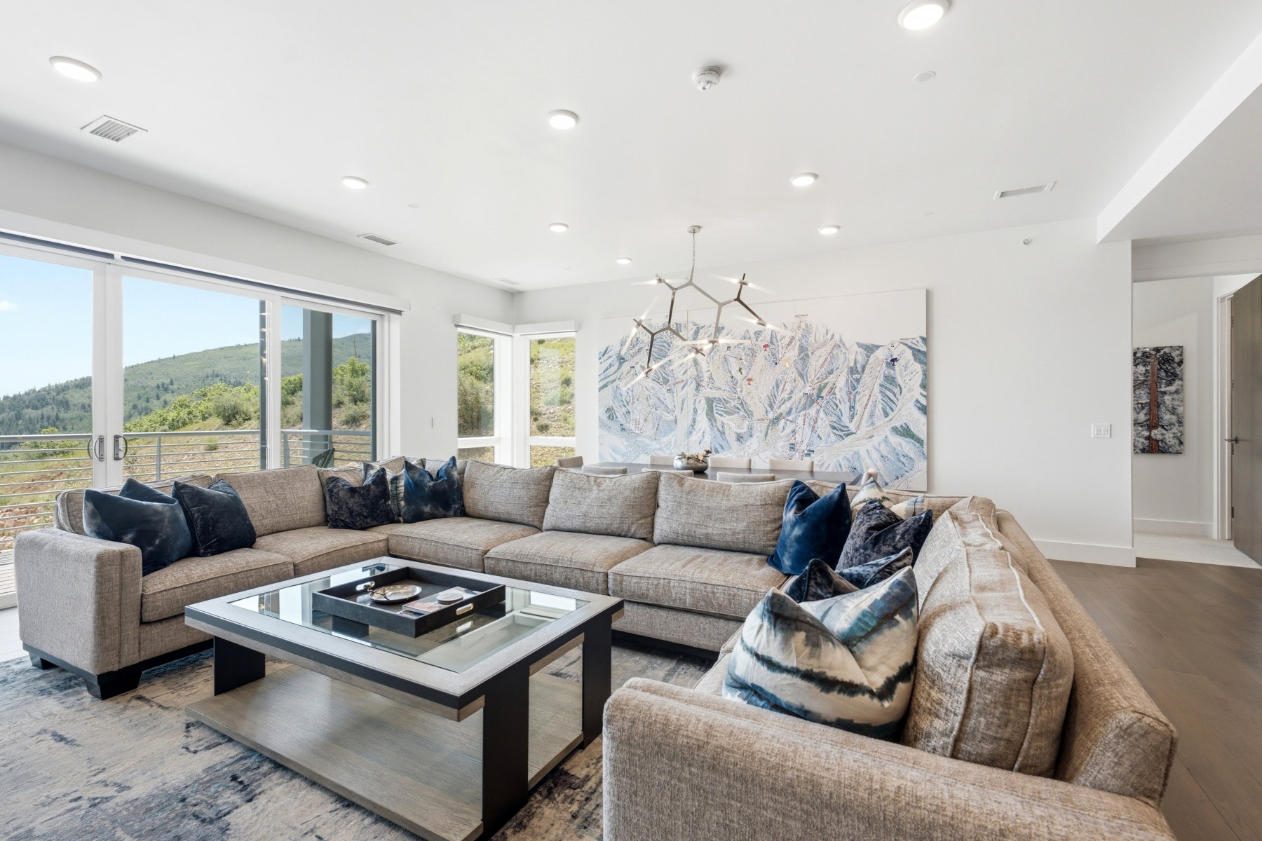 Spacious living area featuring large sliding glass doors, recessed lighting, wood-finish flooring, and a contemporary chandelier