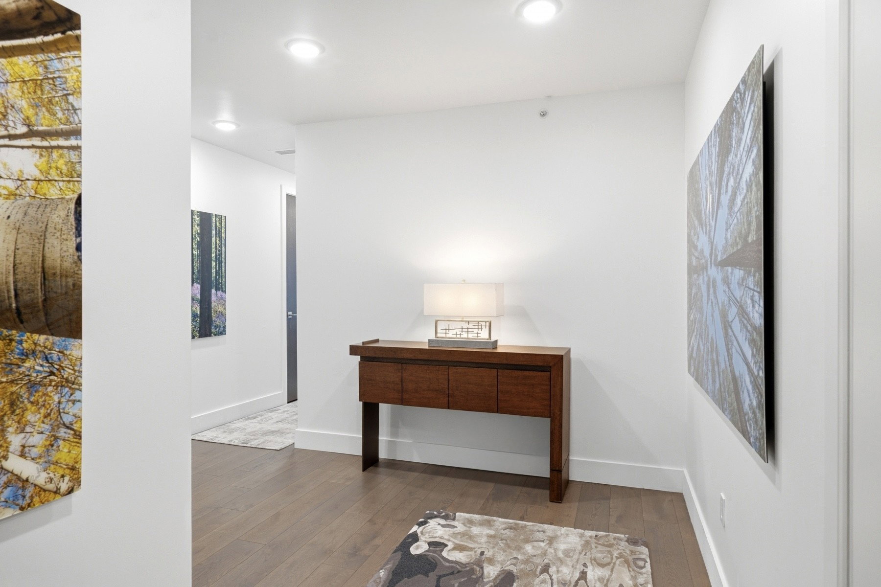 Hallway featuring wood-finish flooring, recessed lighting, white walls, and white baseboards