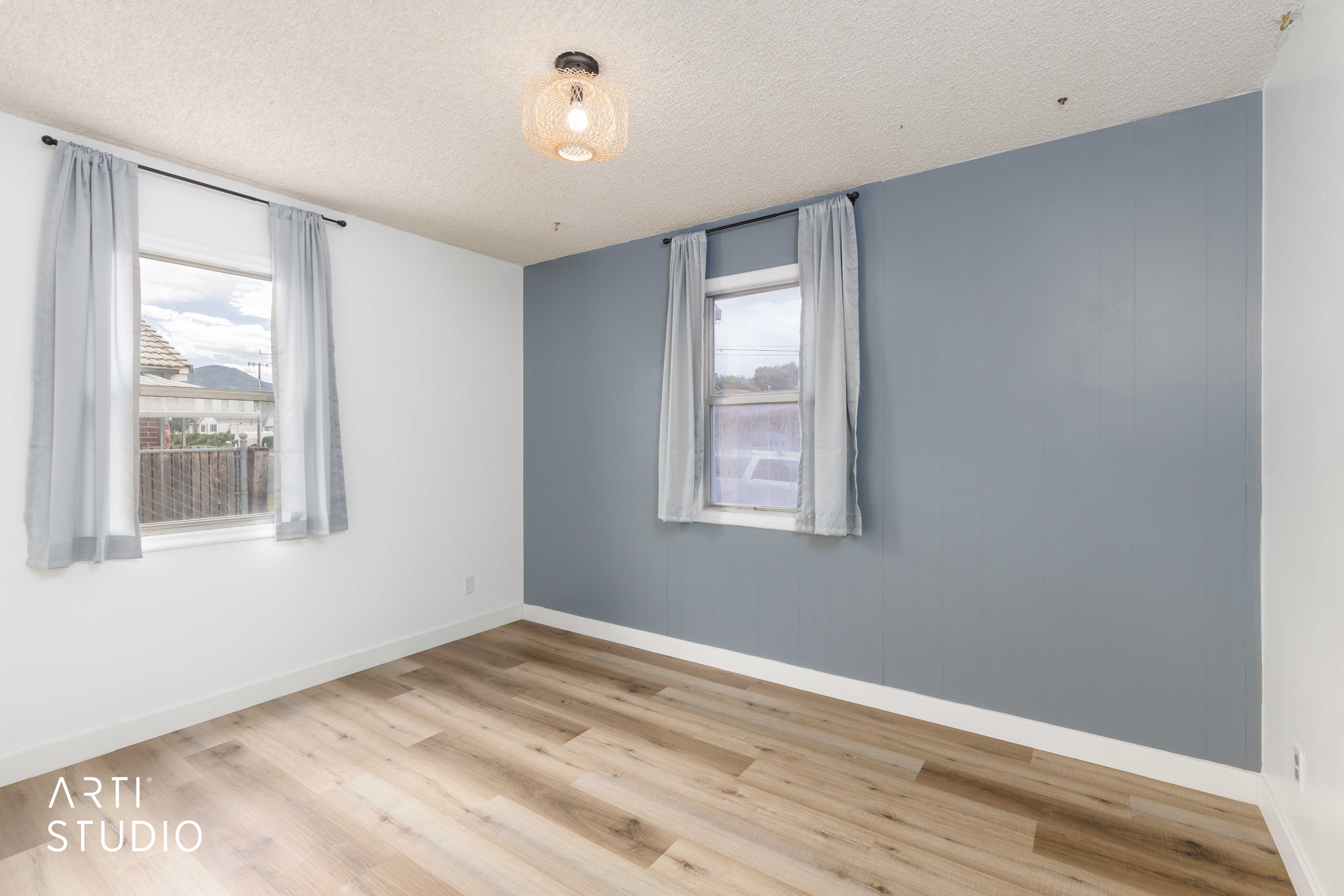 Room featuring wood-finish flooring, white baseboards, and a contemporary ceiling light fixture