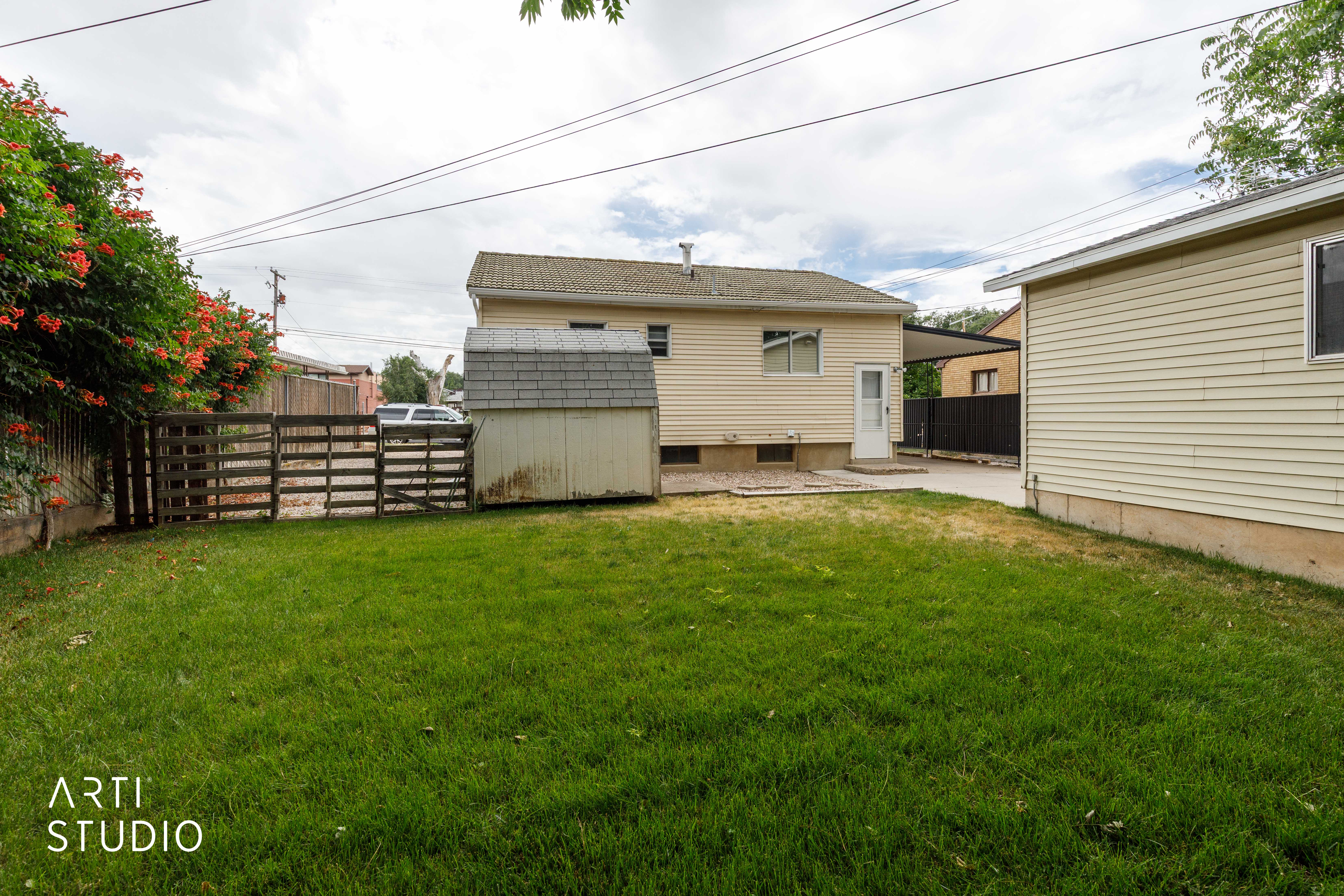 Expansive green lawn with a garden shed and a wooden fence