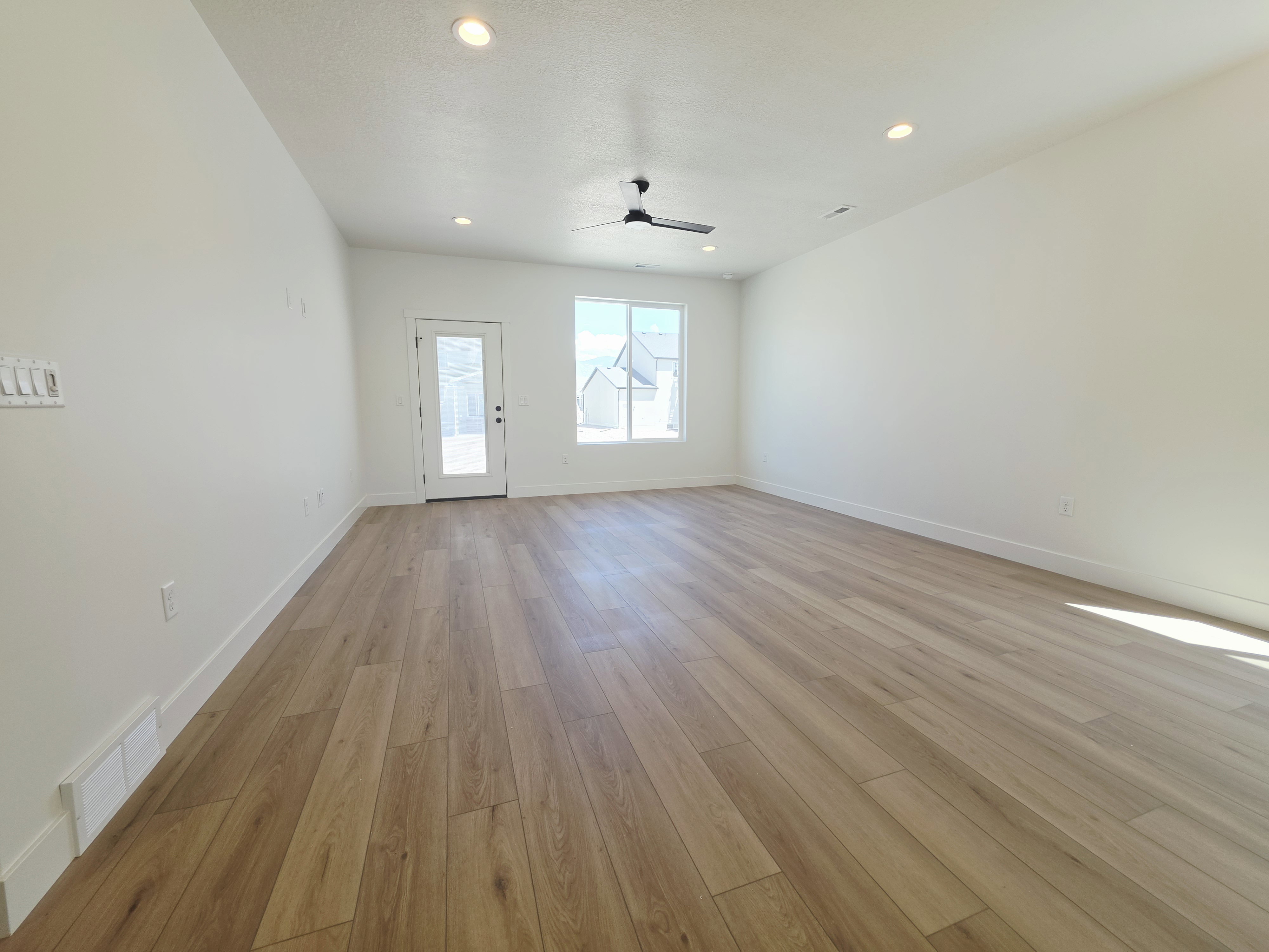 Spacious room featuring wood-finish flooring, recessed lighting, and a contemporary ceiling fan