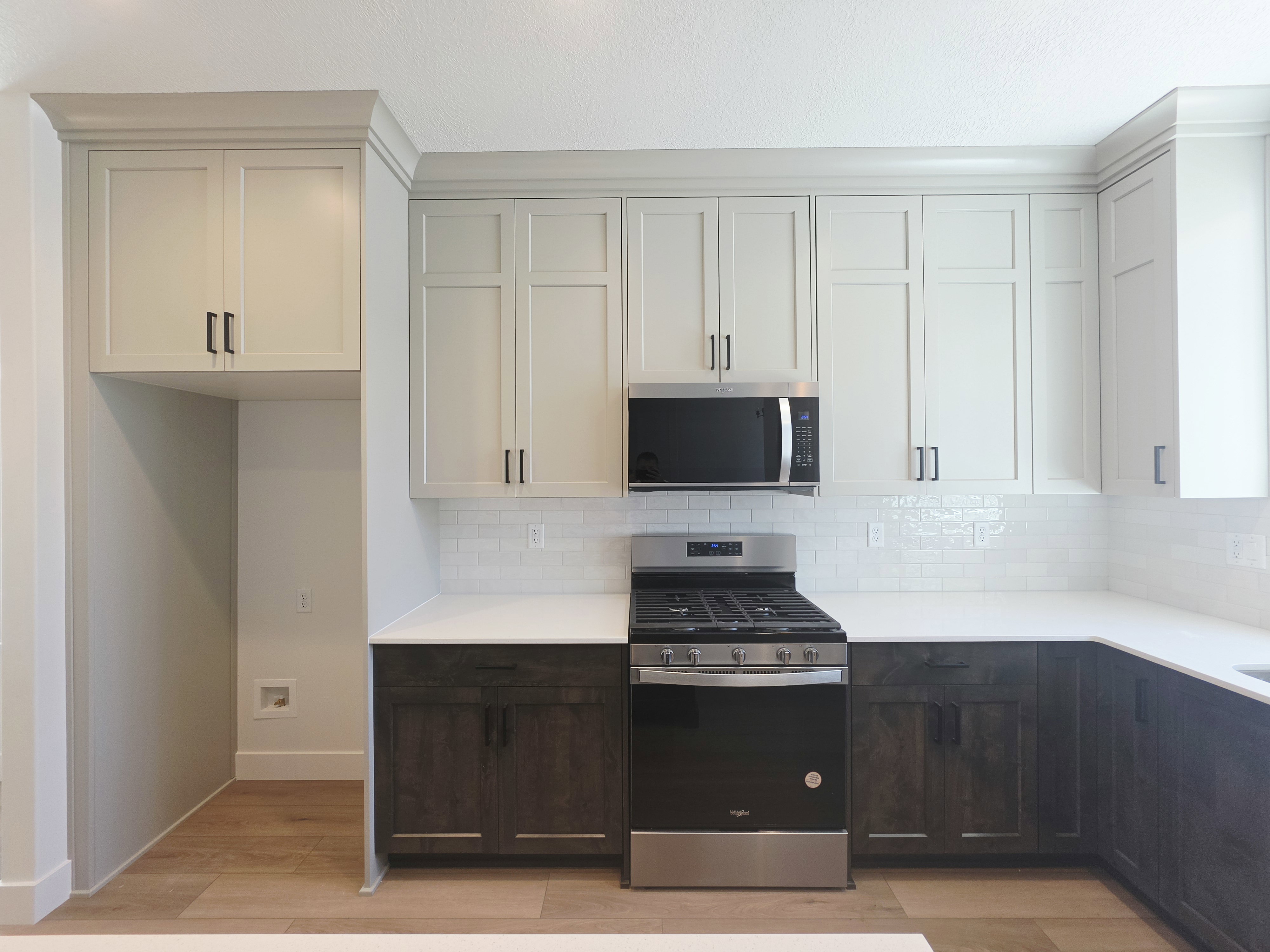 Contemporary kitchen featuring two-tone cabinetry, white countertops, and a subway tile backsplash