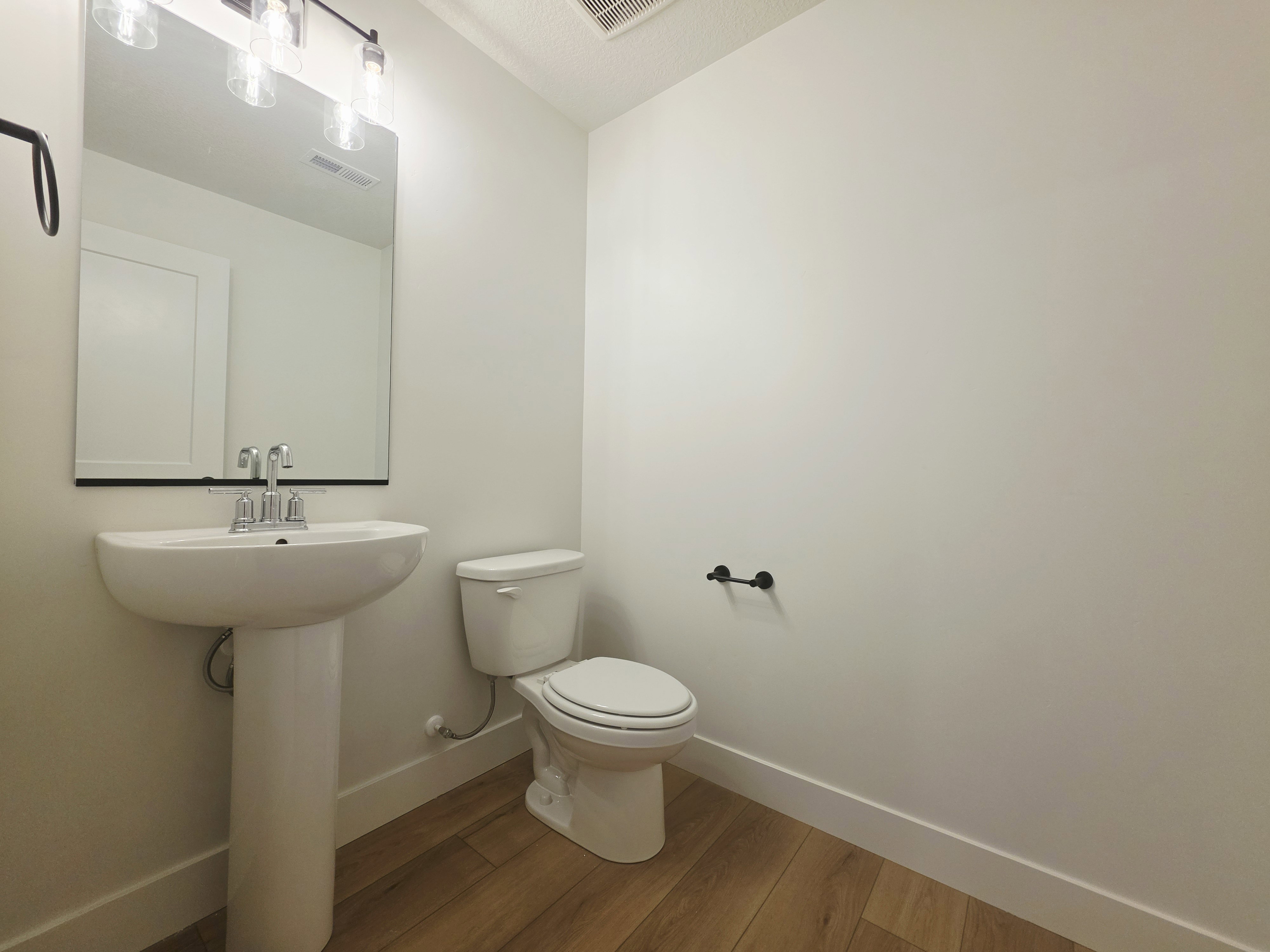 Pedestal sink with chrome faucet, large rectangular mirror, and four-light vanity fixture