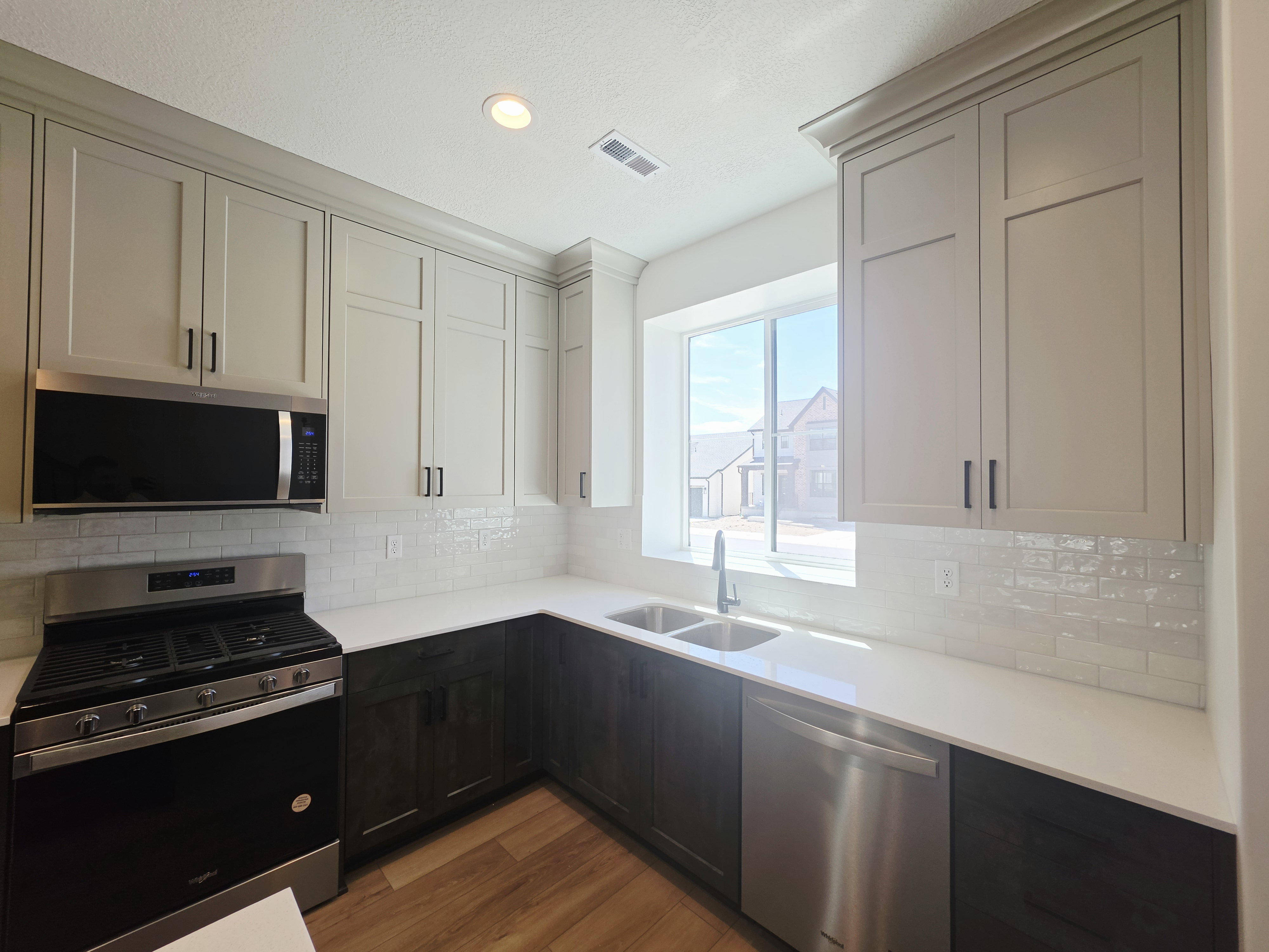 Modern kitchen featuring two-tone cabinetry, white subway tile backsplash, white countertops, and stainless steel appliances