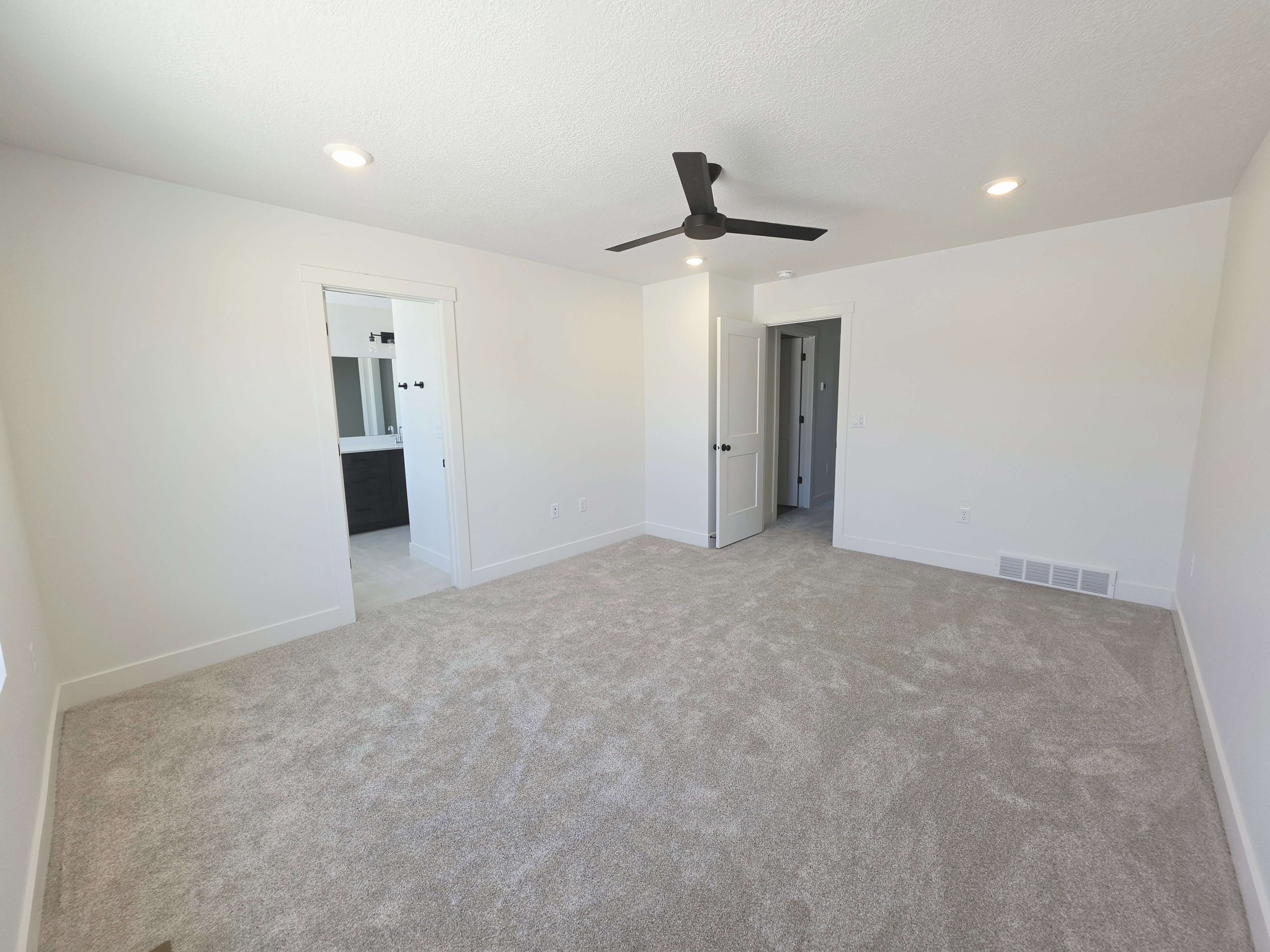 Spacious room featuring light-colored carpeting and white walls