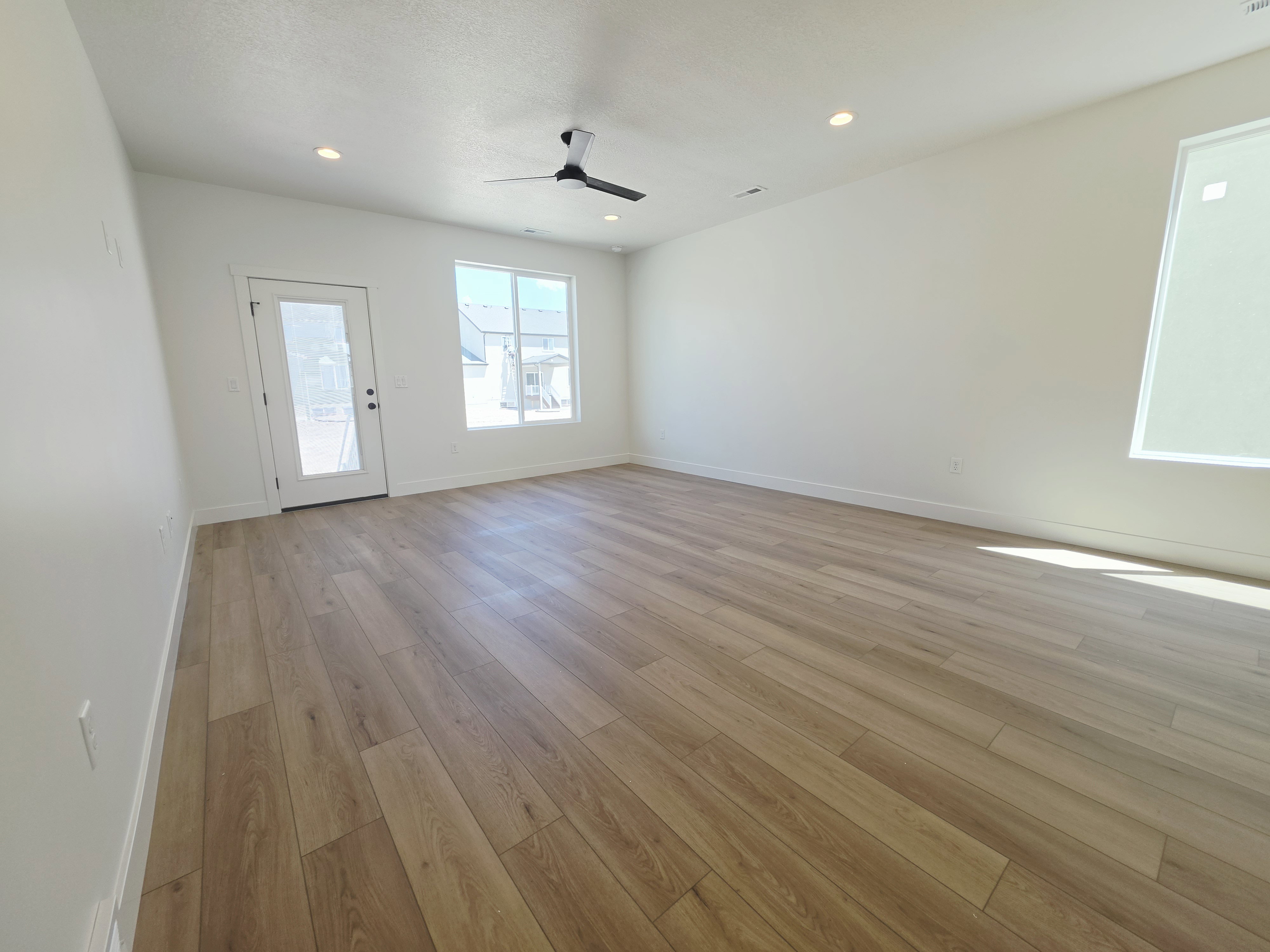 Spacious room featuring light wood-finish flooring, recessed lighting, and a modern ceiling fan