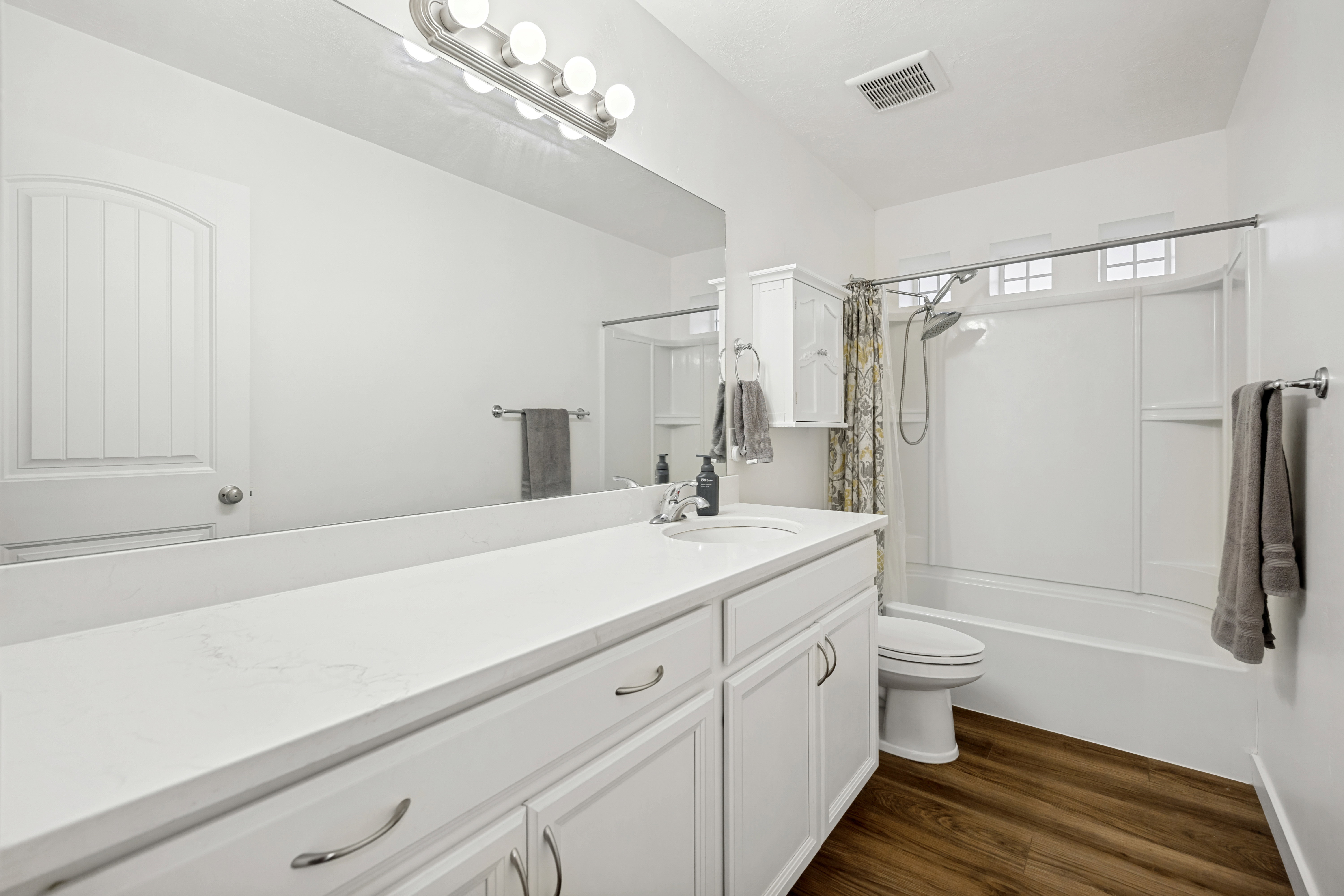 Bathroom featuring a white vanity with an integrated sink, polished chrome hardware, and a large wall mirror