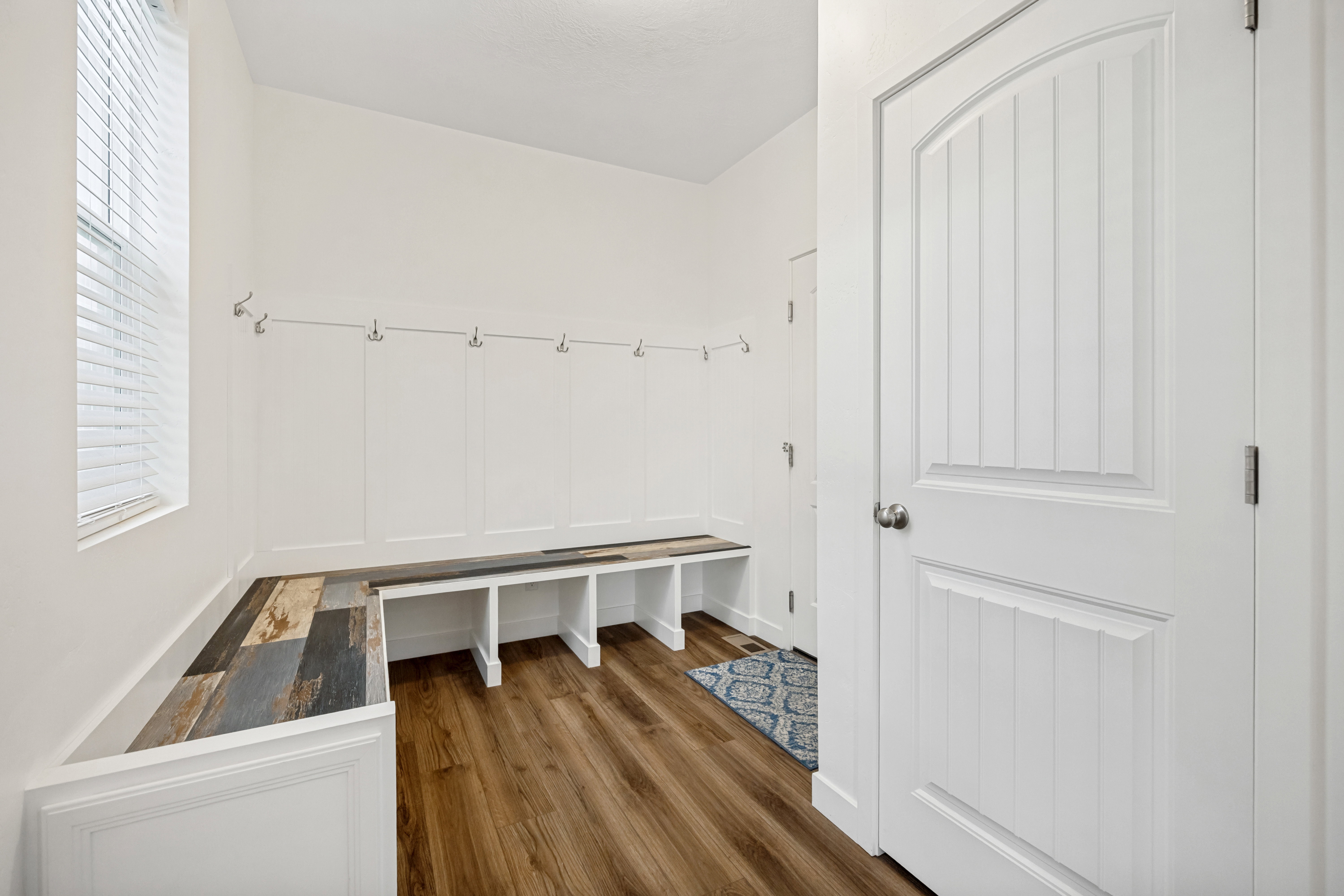 Entryway with built-in bench seating and storage, featuring wood-finish flooring