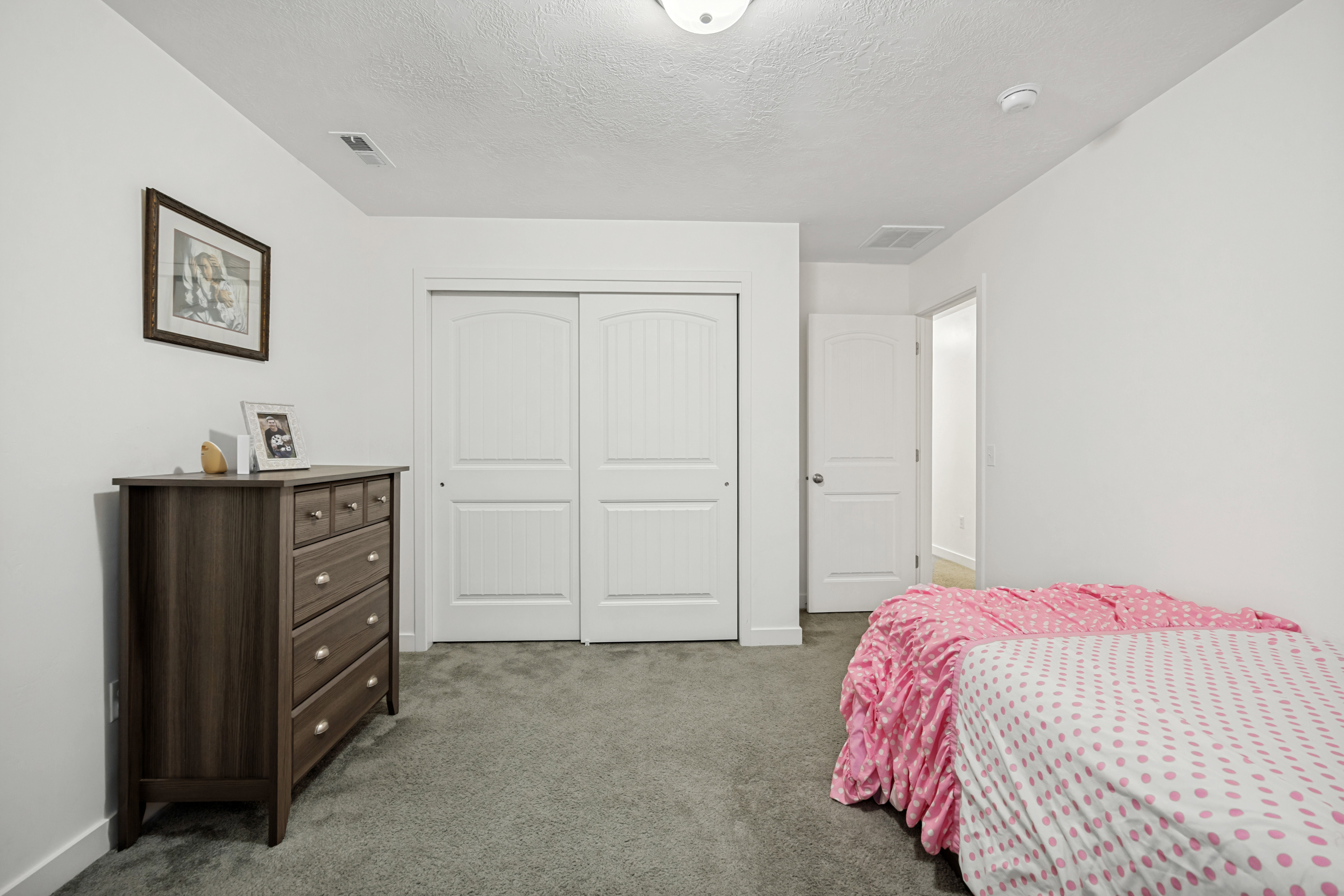 Spacious room featuring neutral carpeting, white walls, and a ceiling-mounted light fixture