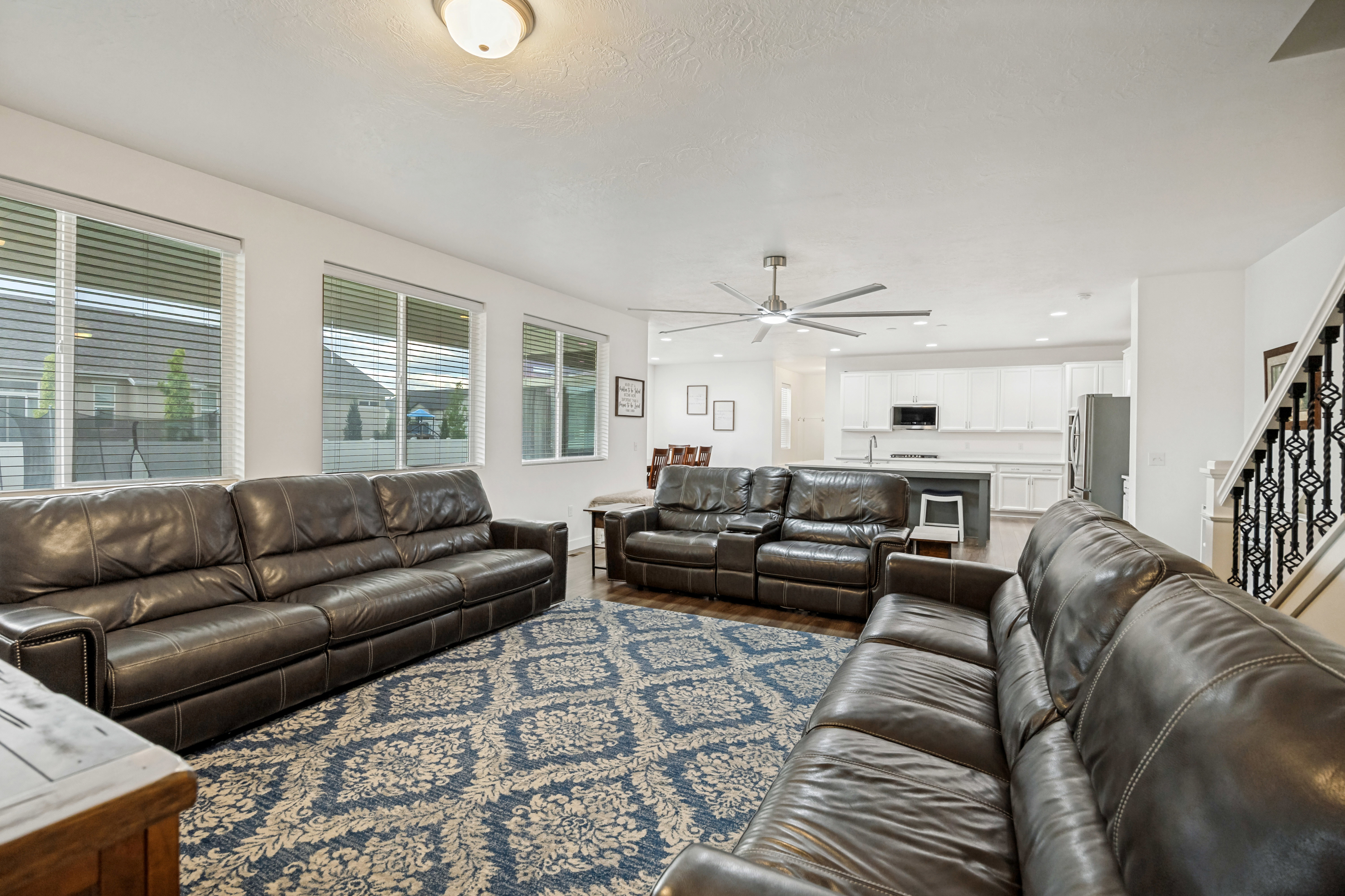 Open-concept living area featuring wood-finish flooring, multiple windows with blinds, and a contemporary ceiling fan