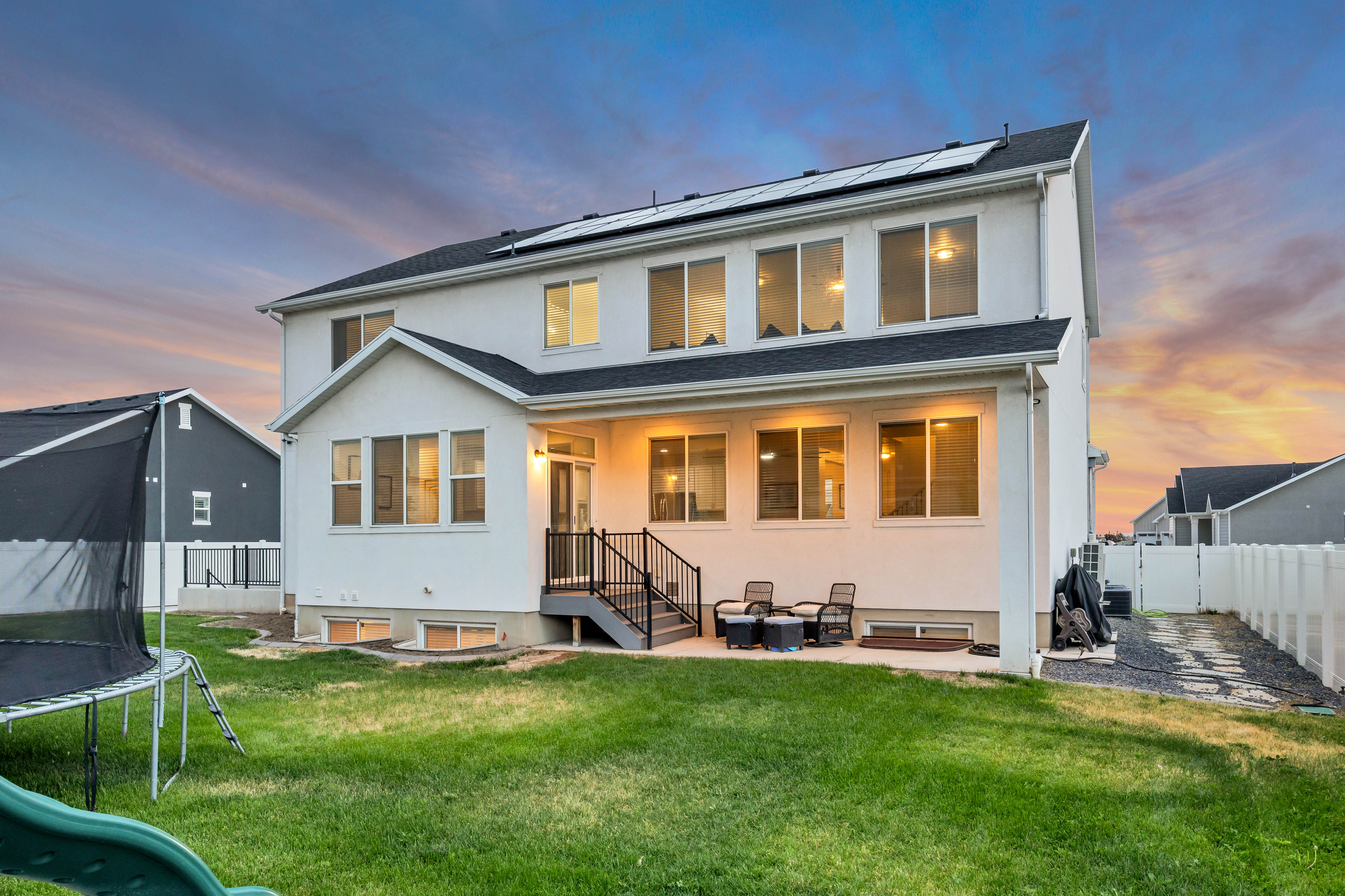 Two-story home with a covered patio, multiple windows, and solar panels