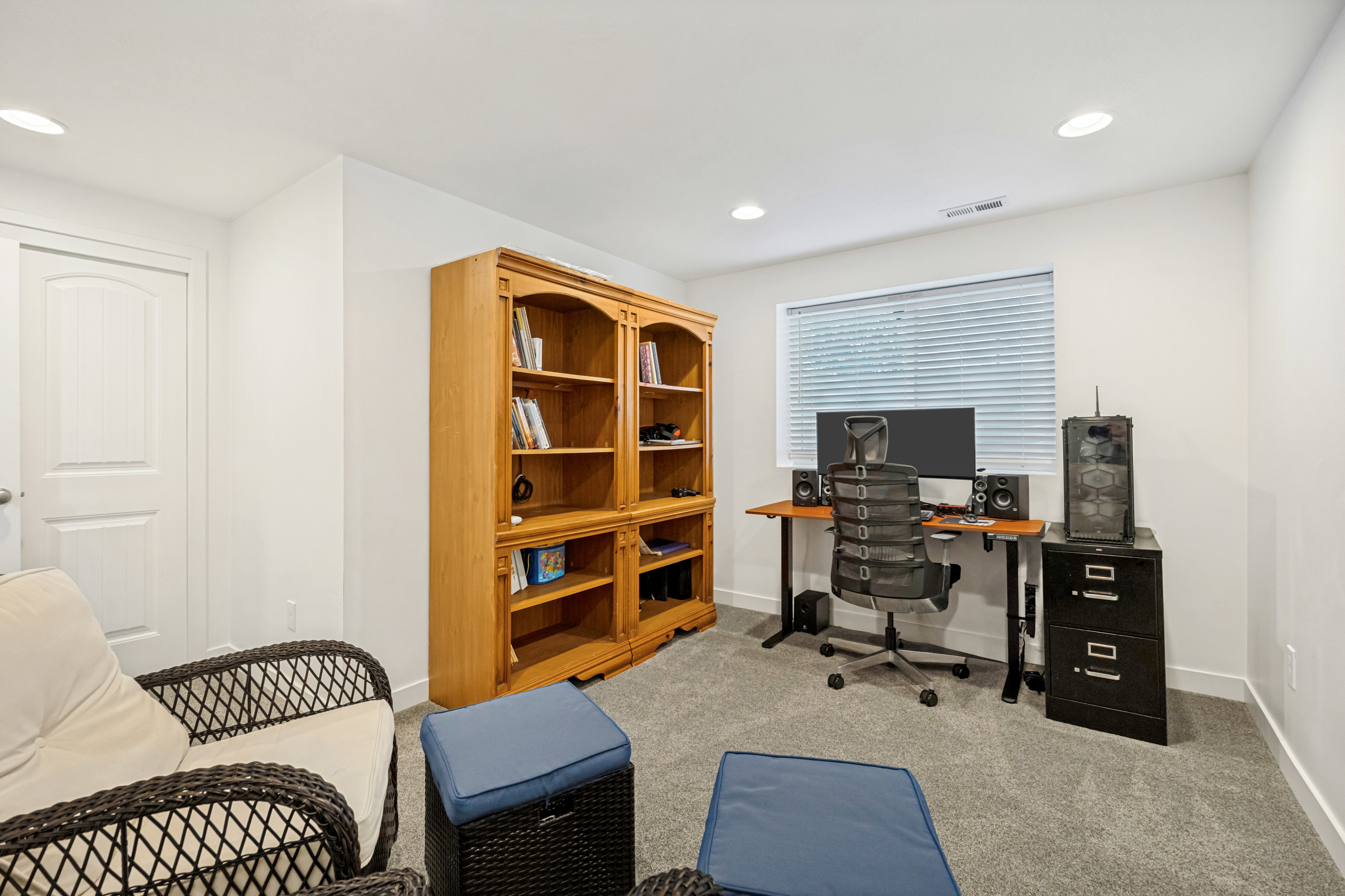 Carpeted room featuring a window with blinds, recessed lighting, and a white interior door