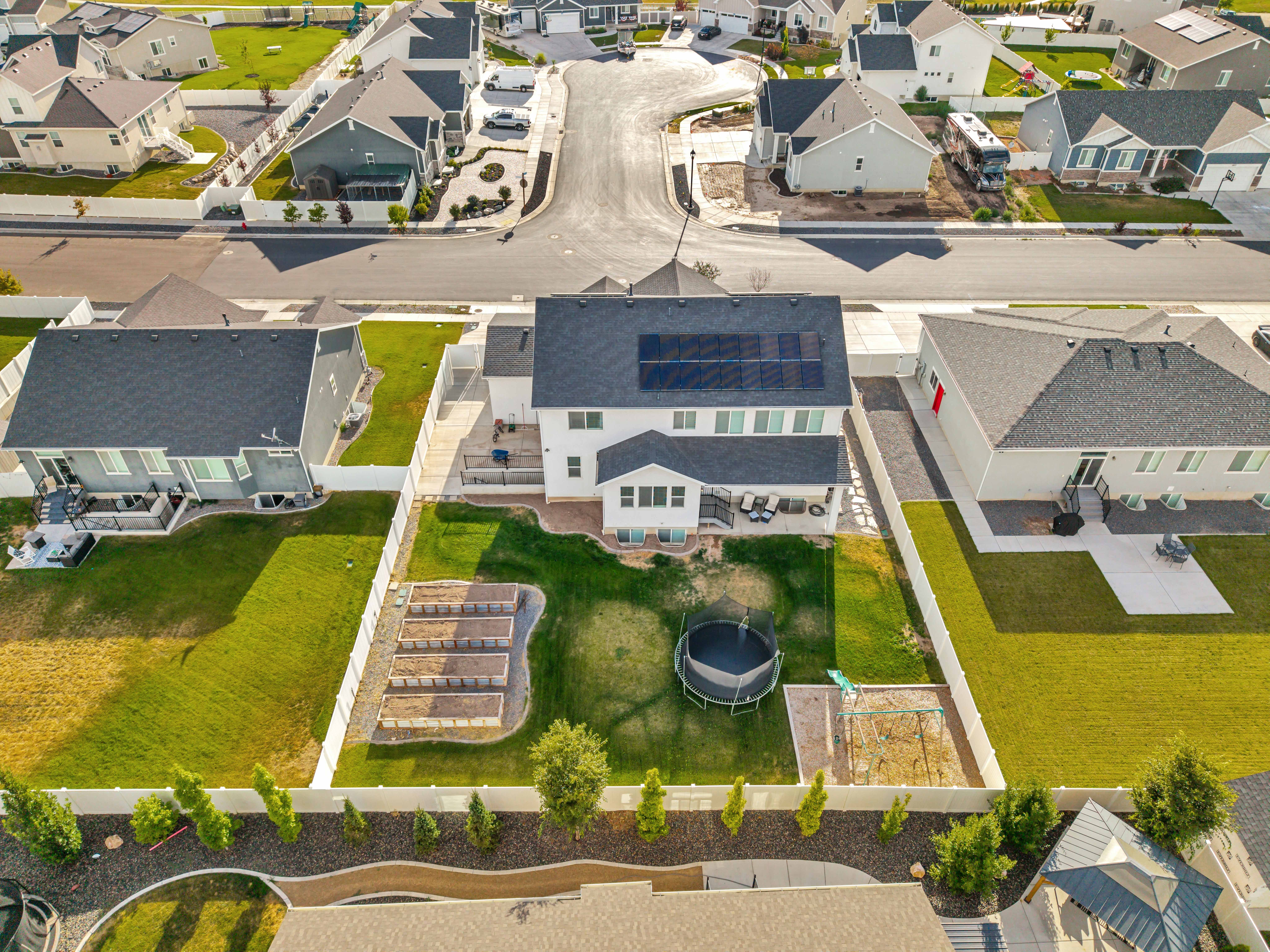 White residential structure featuring a gray shingled roof with solar panels