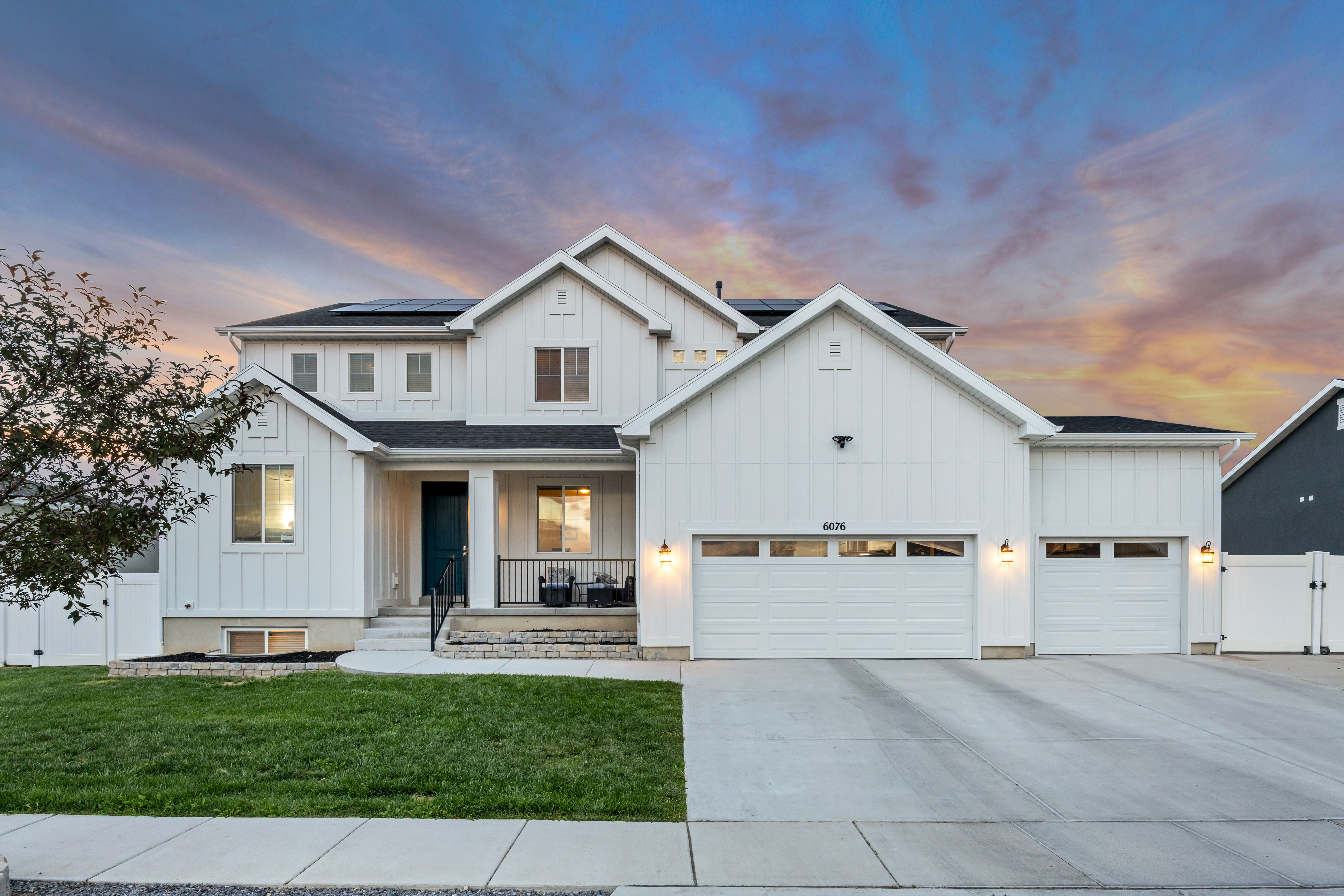 Modern farmhouse-style exterior with white board and batten siding, a dark roof, and multiple gables