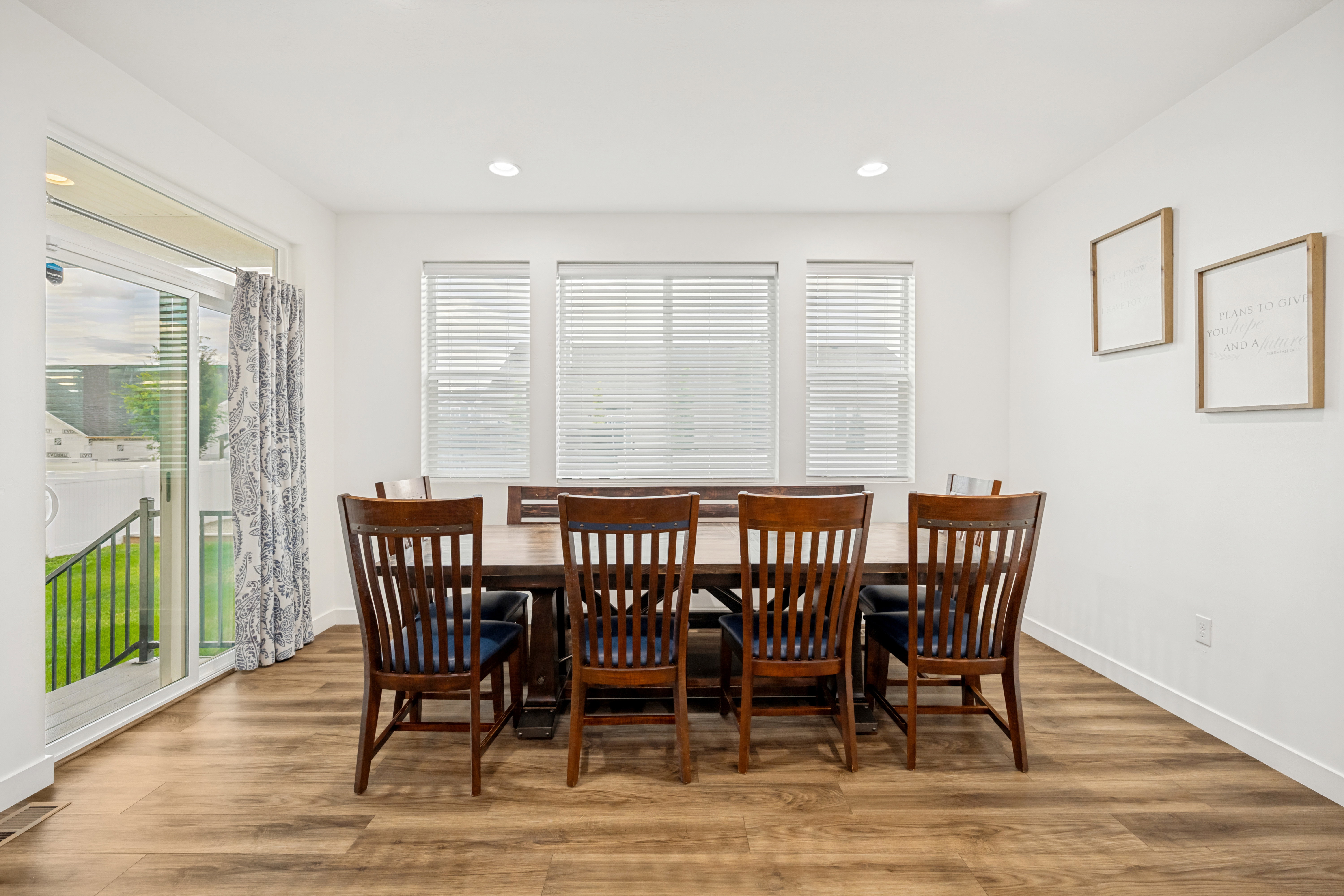 Bright interior space featuring wood-finish flooring, recessed lighting, and three large windows with horizontal blinds
