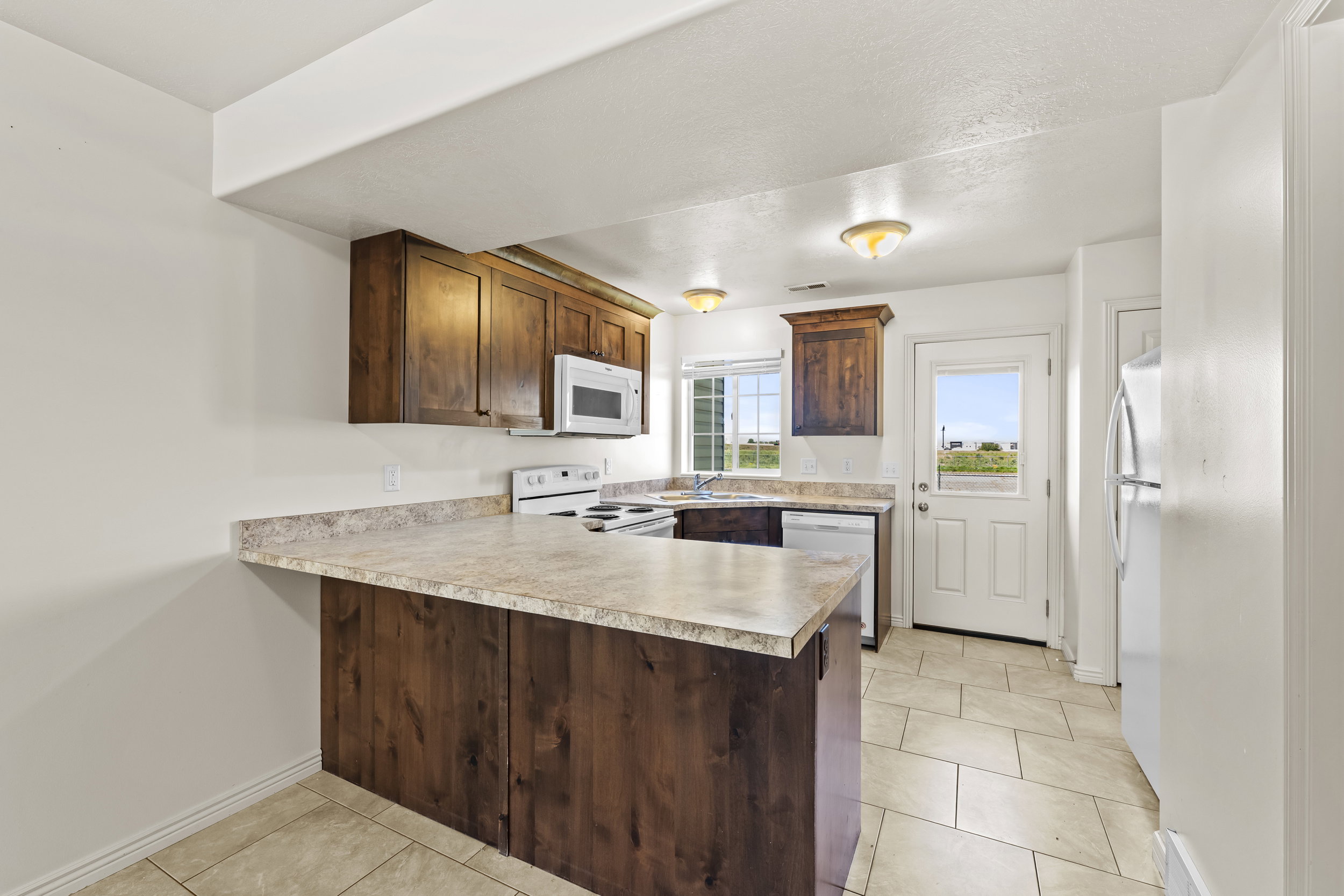 Kitchen featuring wood-finish cabinetry, laminate countertops, and tile flooring