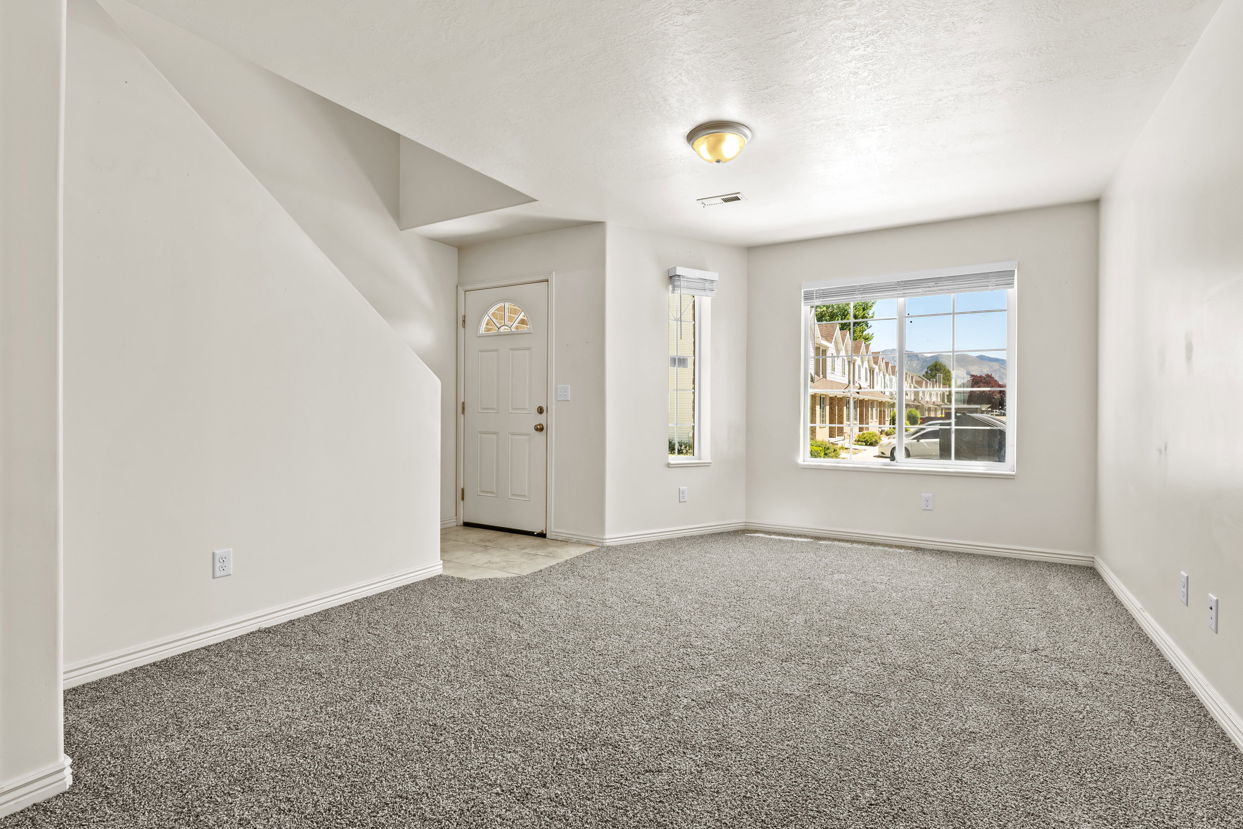 Spacious living area featuring neutral-toned carpeting and light-colored walls
