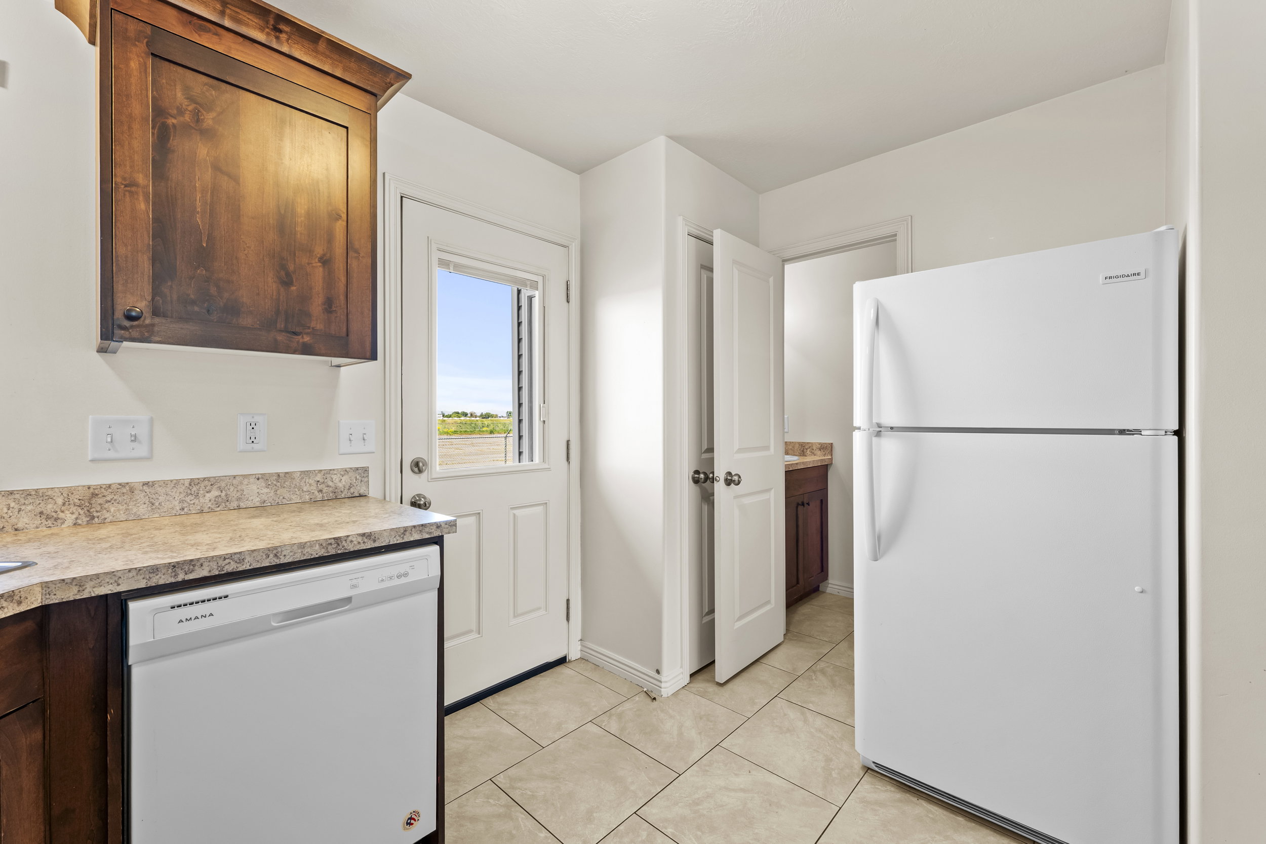 Kitchen area featuring tile flooring, a white dishwasher, and a white refrigerator