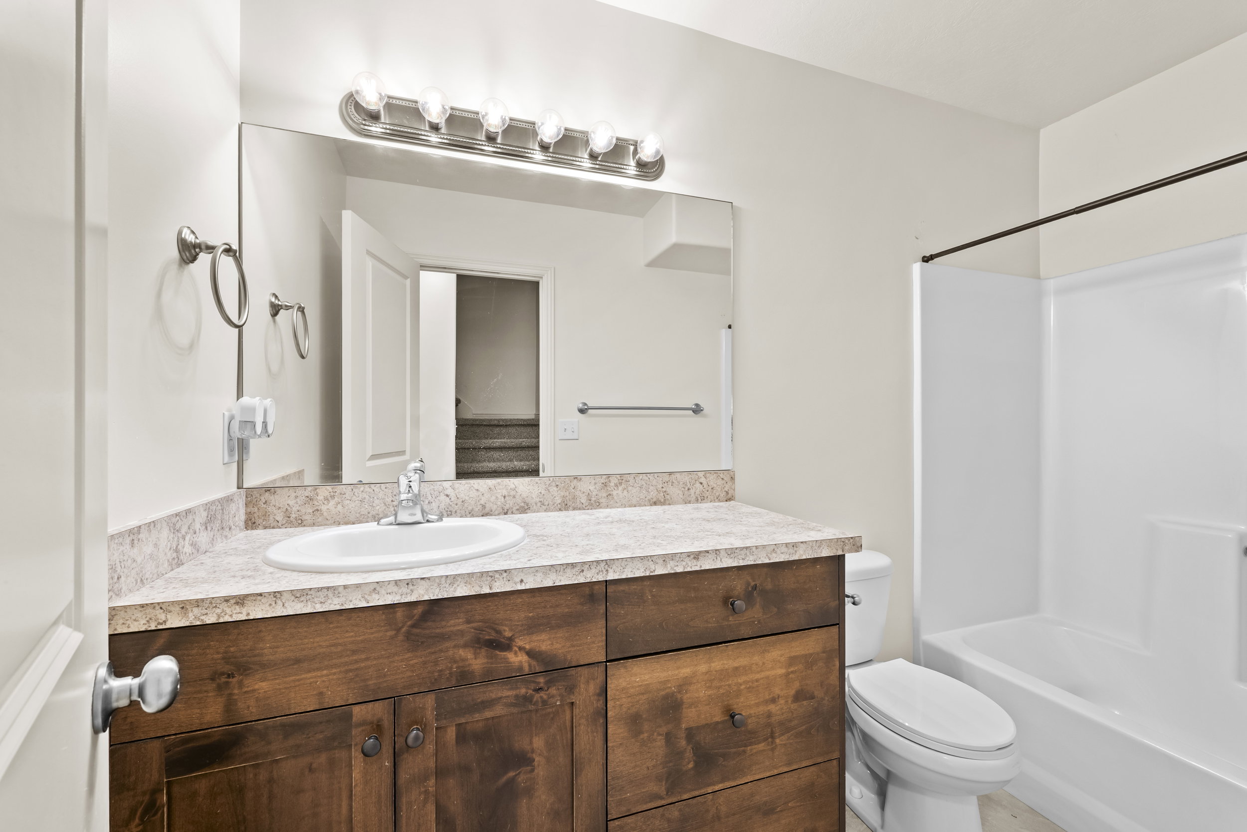 Bathroom featuring a dark wood-finish vanity with a light-toned countertop, an oval undermount sink, and a chrome faucet