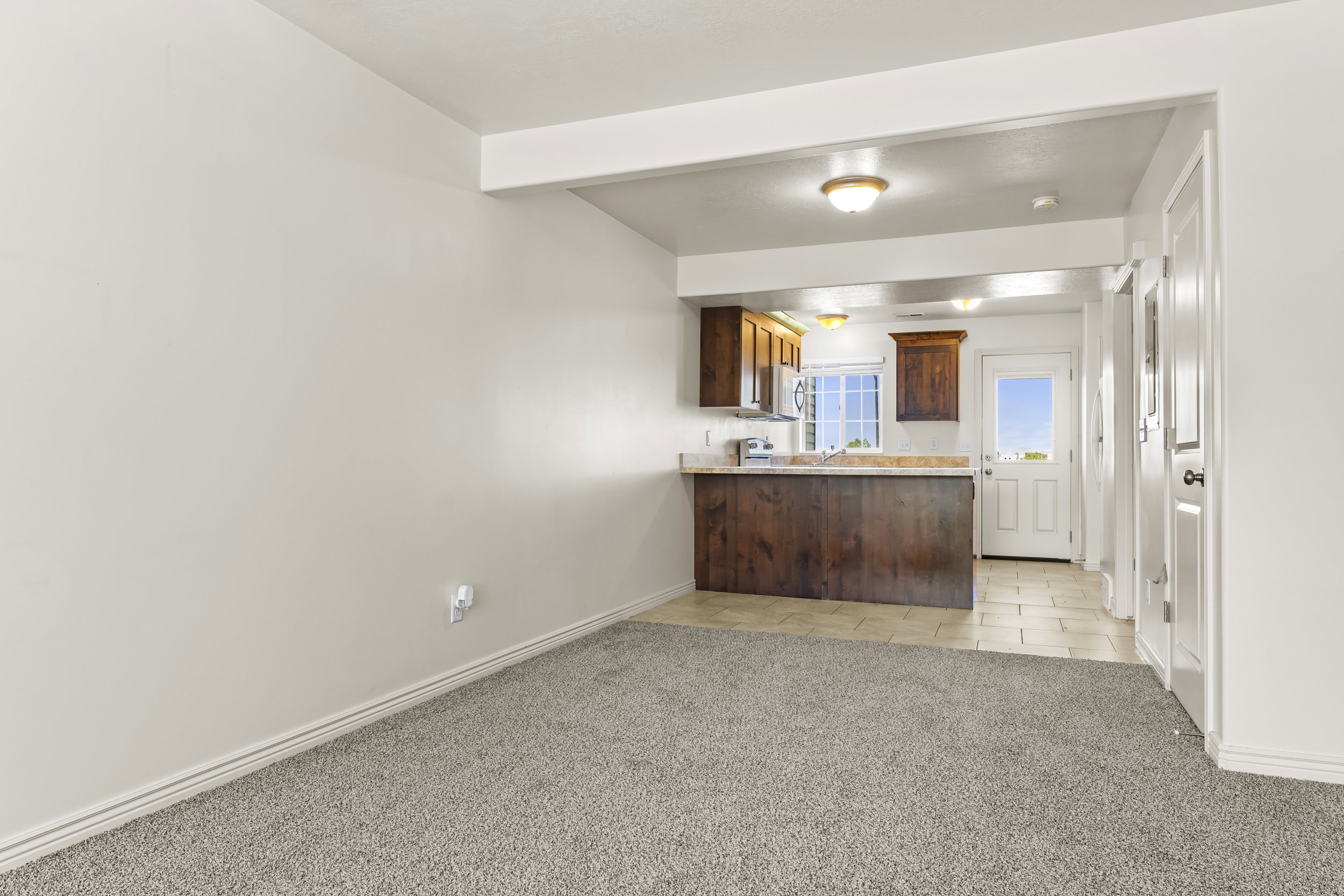 Open-concept room featuring gray carpet flooring and white baseboards