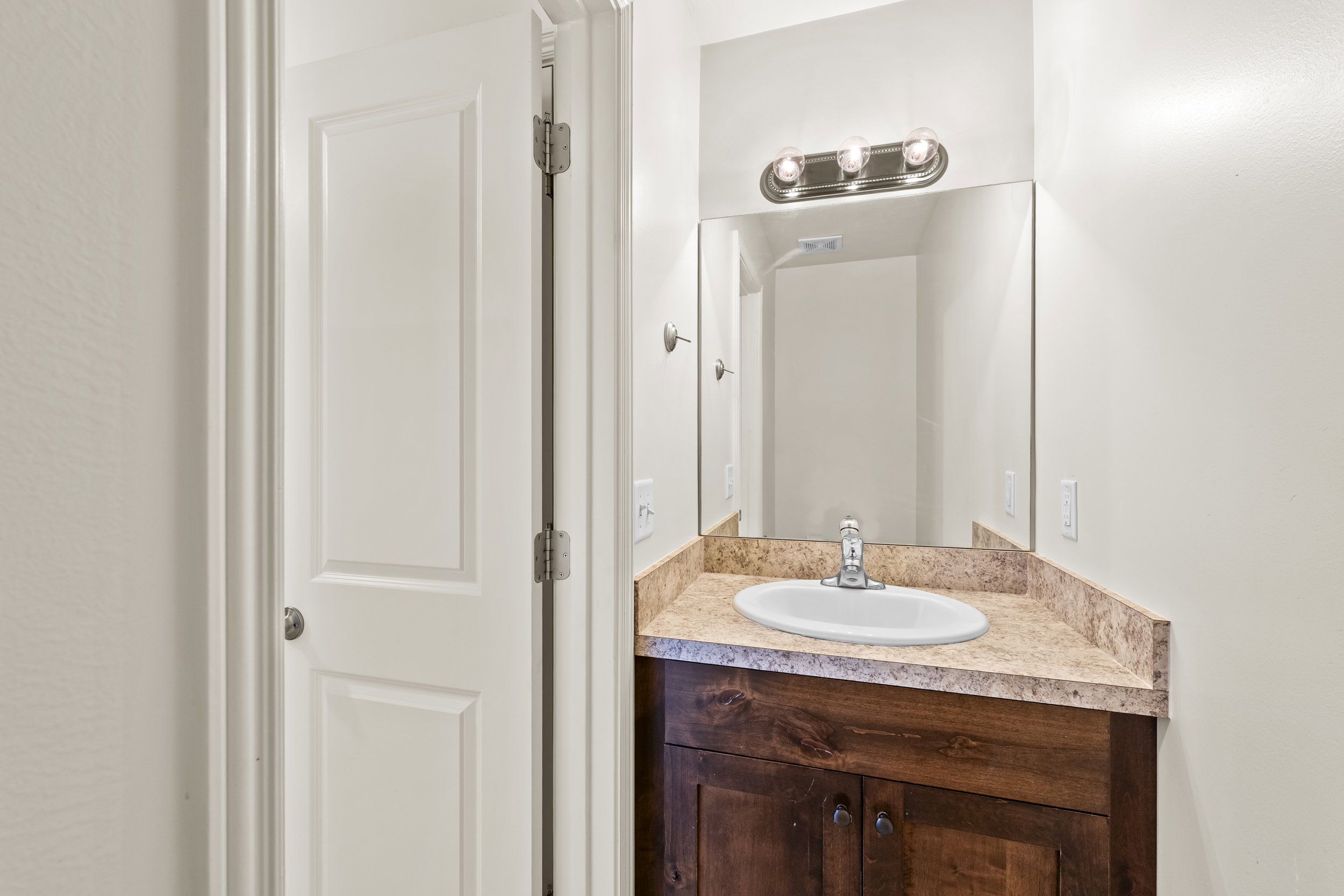 Vanity with a wood-finish cabinet, a single basin sink, and a speckled countertop