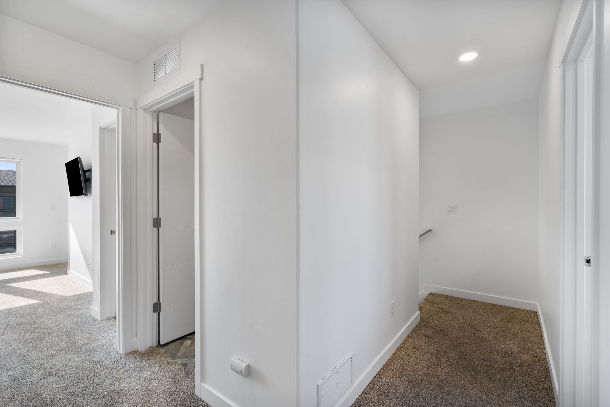 Hallway with neutral carpet, white walls, and recessed lighting