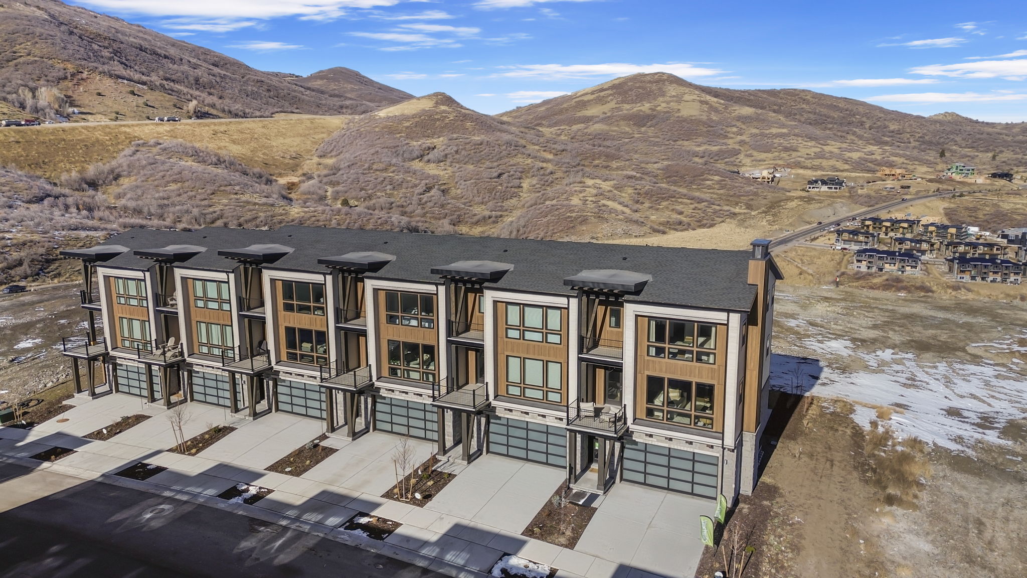 Contemporary townhome exteriors featuring multi-story designs, large windows, and attached garages with modern glass panel doors