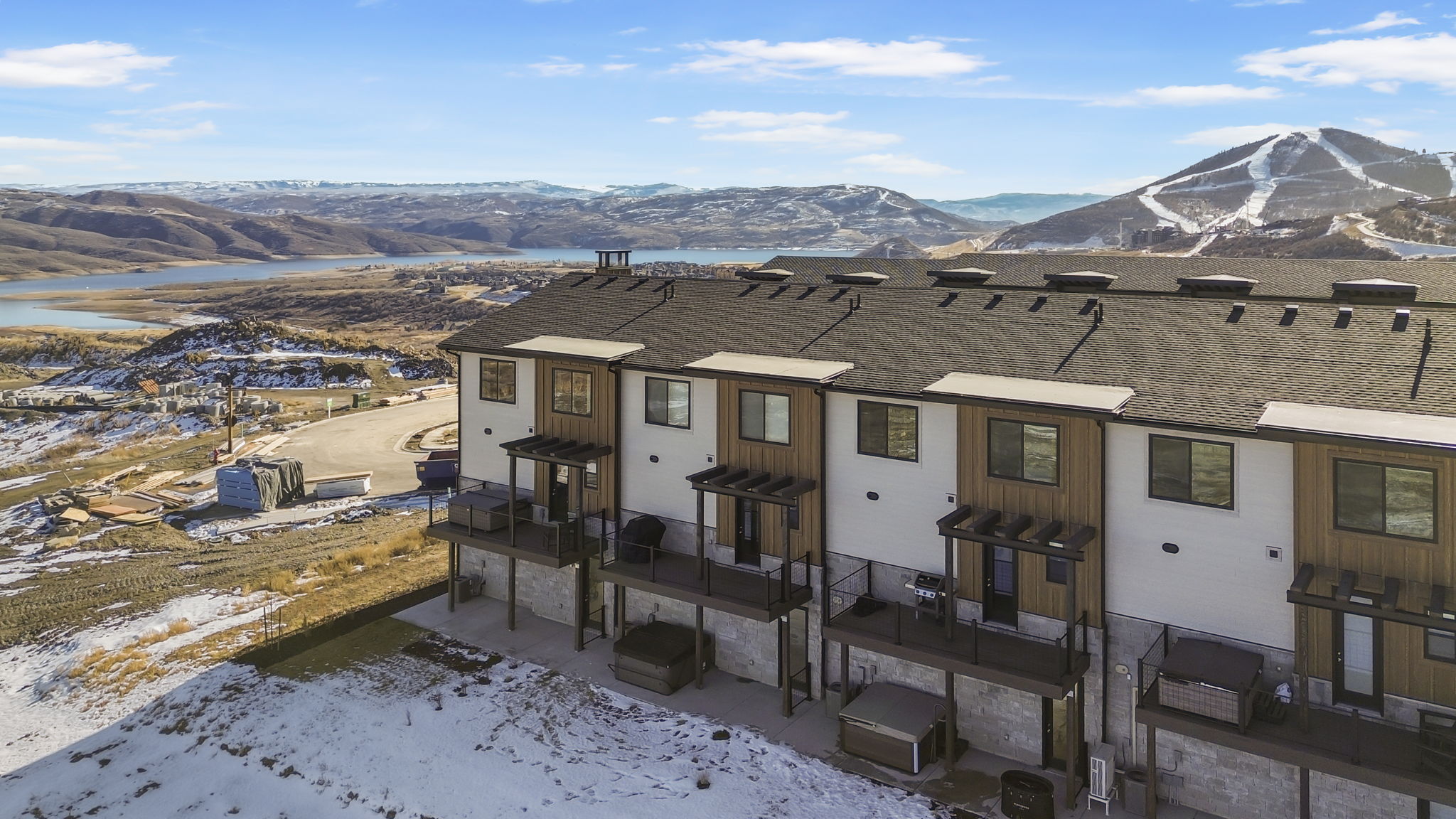 Multi-level townhomes featuring balconies, dark framed windows, and wood-panel accents
