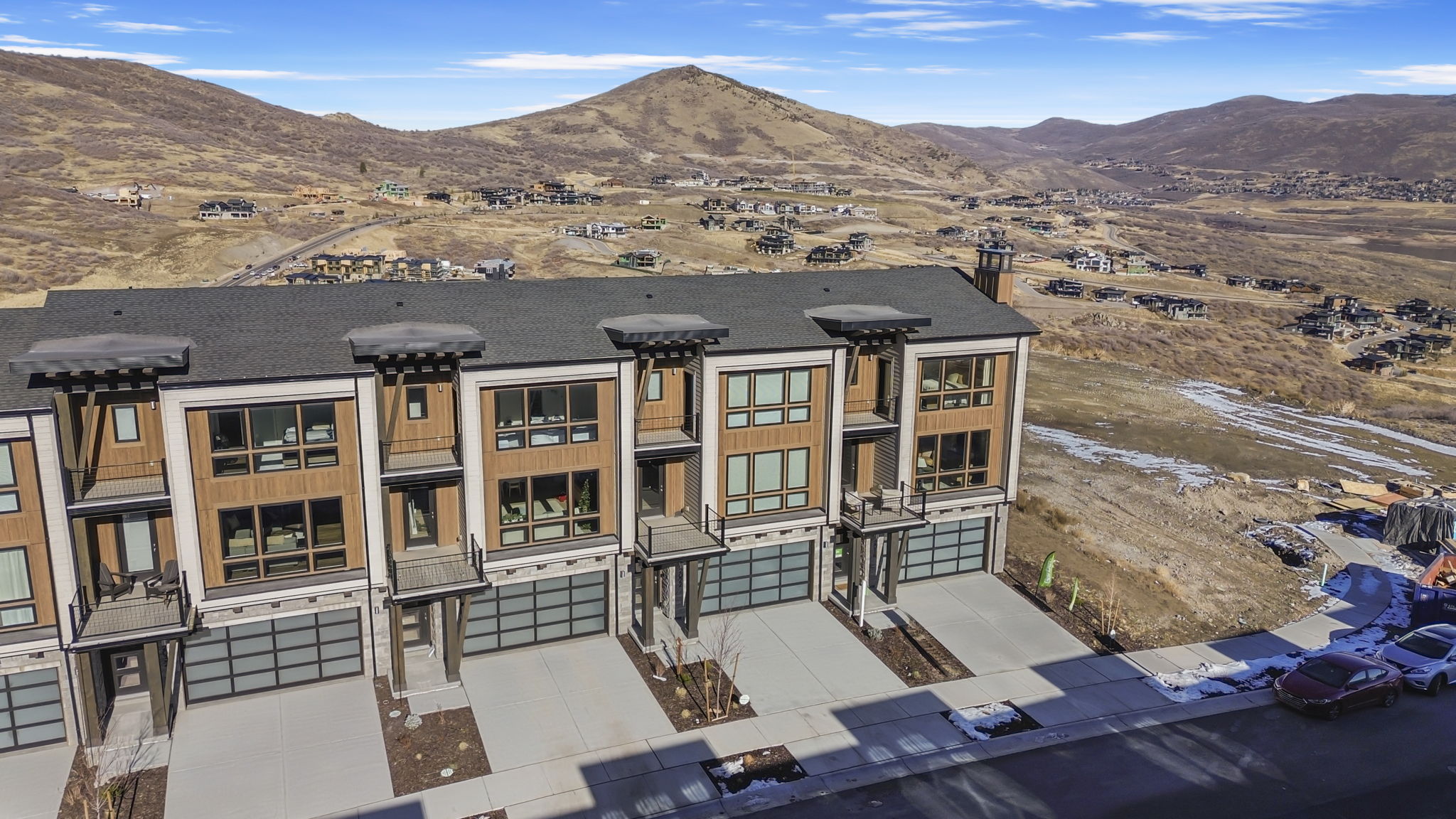 Modern townhome exterior featuring multiple large windows, wood-panel siding, and contemporary garage doors with frosted glass panels