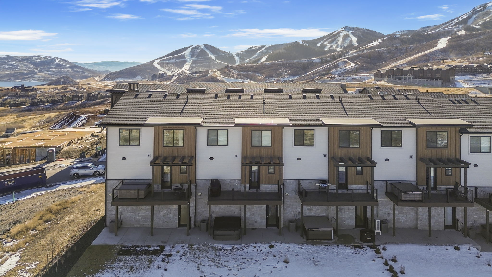 Modern townhome exteriors featuring white siding, wood-finish paneling, and stone-clad lower levels