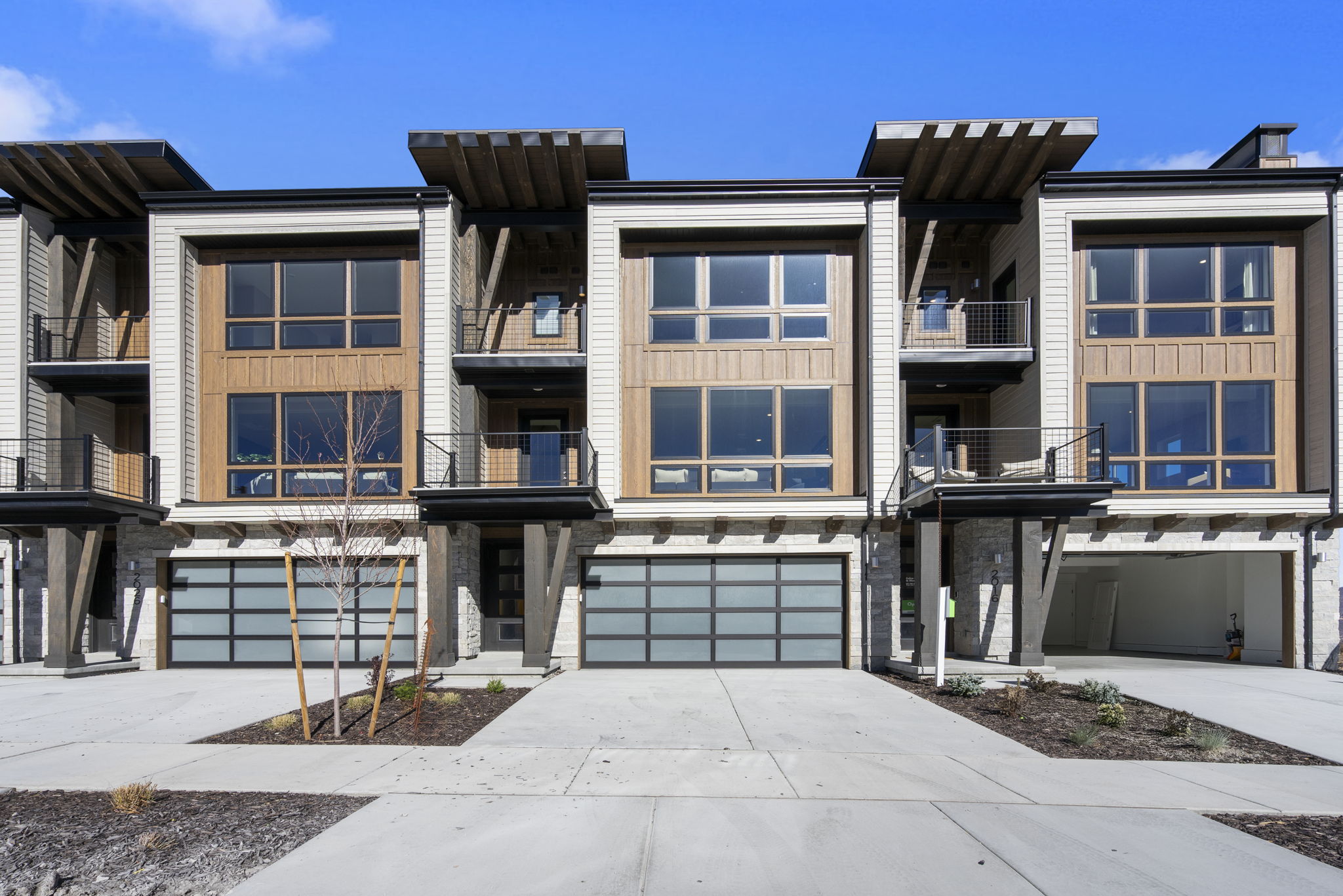 Modern townhome exterior featuring vertical siding, wood-finish paneling, and stone accents